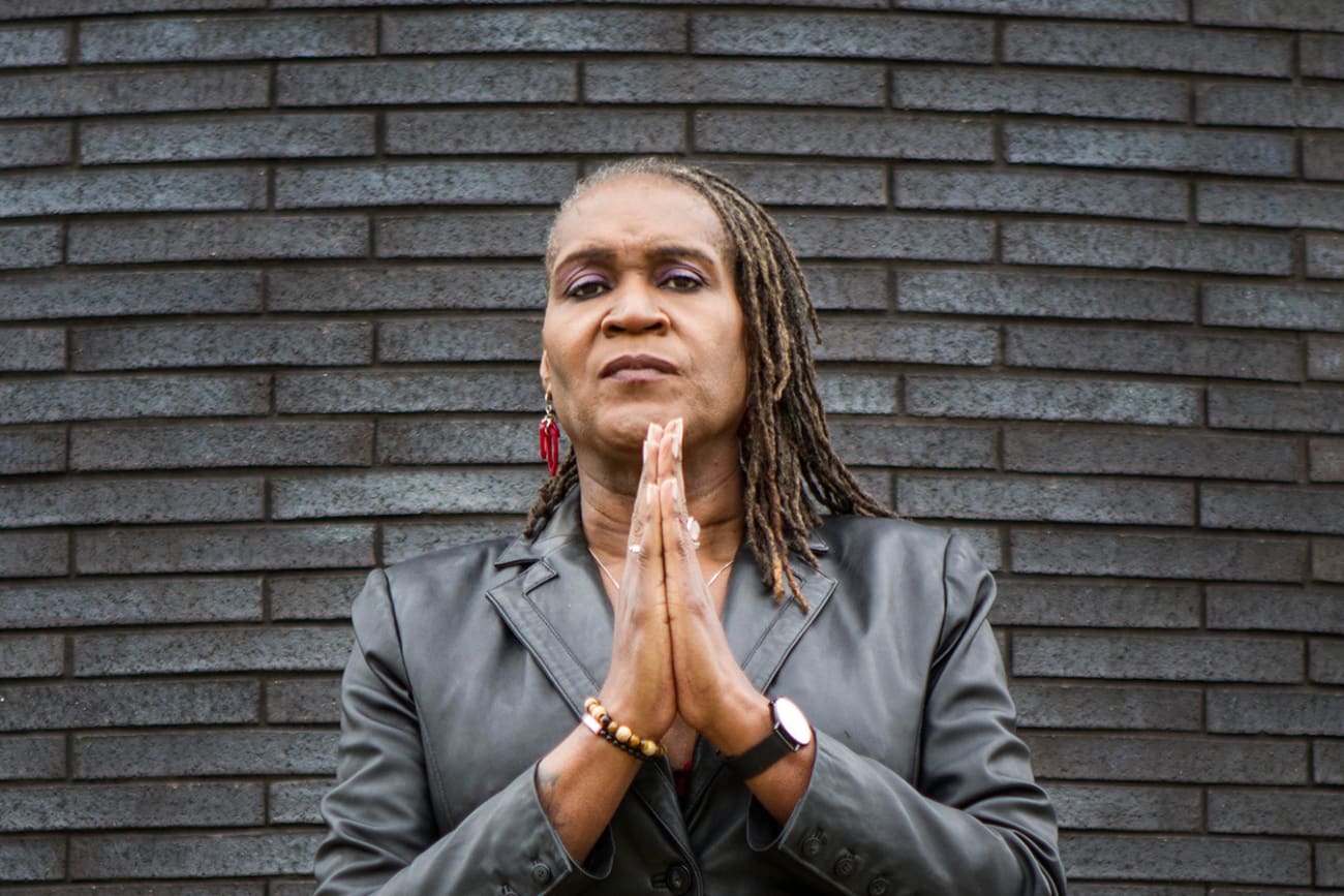 The photo shows the council vice president standing in front of a slate-colored brick wall with her hands together looking at the camera. 