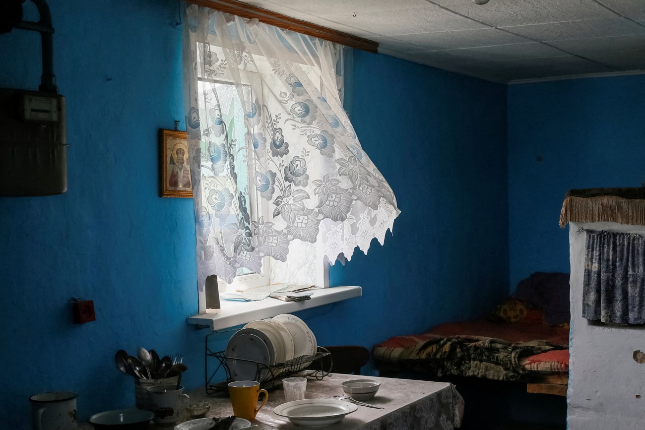 A white lace curtain flutters in the breeze in the window of a kitchen in a home in Kyiv, abandoned by residents during the Russian war on Ukraine, in March 2022.