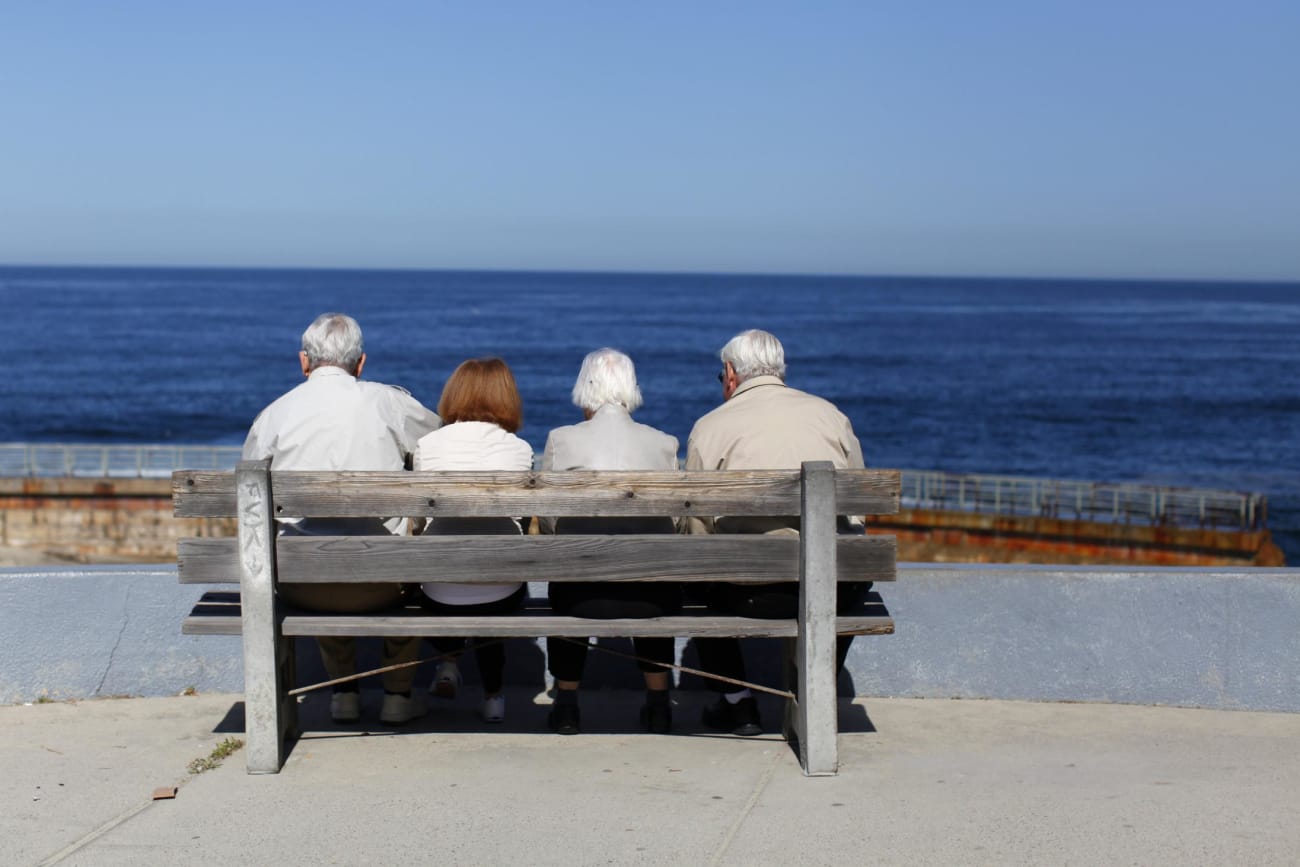 A pair of elderly couples view the ocean and waves along the beach.