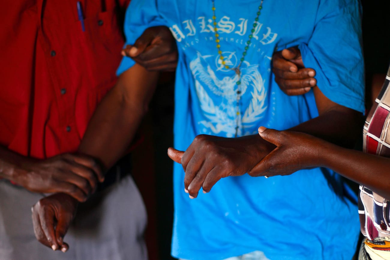 A person with HIV/AIDS is helped to his bedroom by caregivers from a community home-based care team visiting him at his home in Matero township on the outskirts of Lusaka, Zambia on April 17, 2012. The picture shows the torso of a man wearing a loose-fitting light blue shirt being helped by two other people. REUTERS/Darrin Zammit Lupi