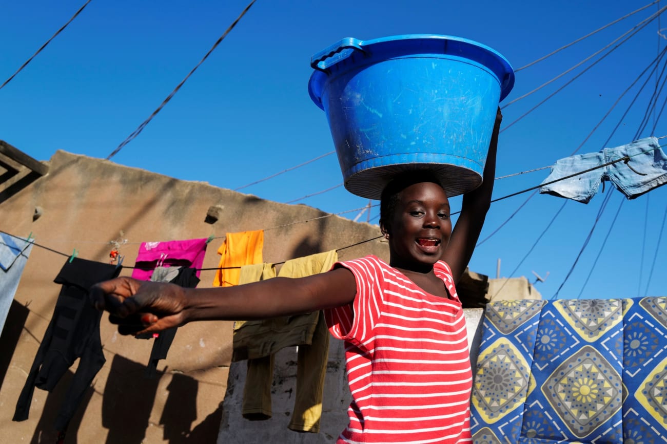 A girl carries a bucket with laundry on her head while heading home as the spread of the coronavirus disease continues, in Yoff neighbourhood, Dakar, Senegal on January 26, 2021.