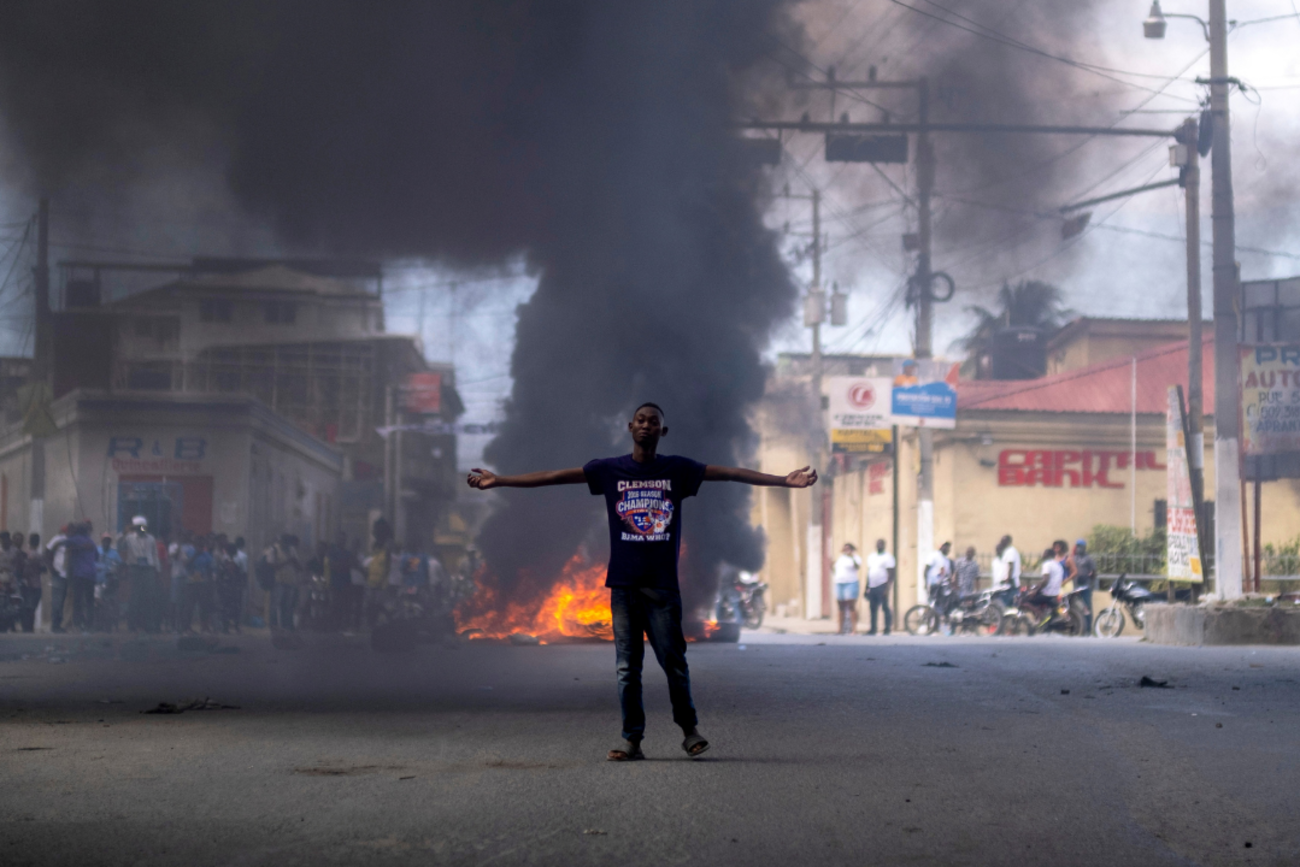 A man stands in front of a burning barricade during a protest against the assassination of Haitian President Jovenel Moise in Cap-Haitien, Haiti on July 22, 2021.