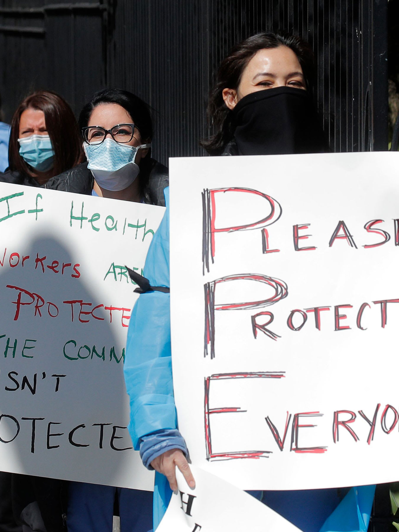 The photo shows a number of nurses lined up holding placards. One of them plays off the term PPE and spells out "Please Protect Everyone." 