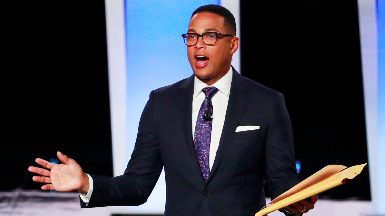 The photo shows the journalist in a smart suit speaking and gesturing with his hands.