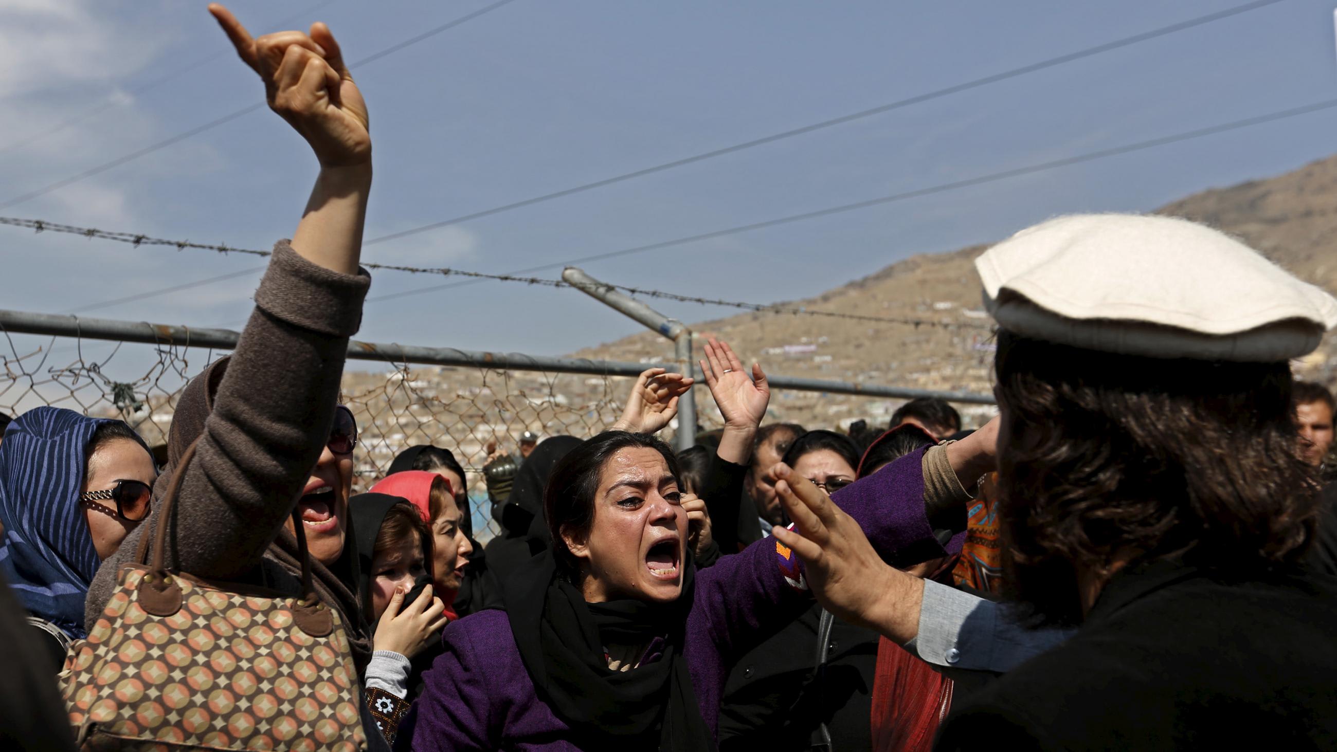 The photo shows a large collection of protesters shouting at someone whose back is to the camera.