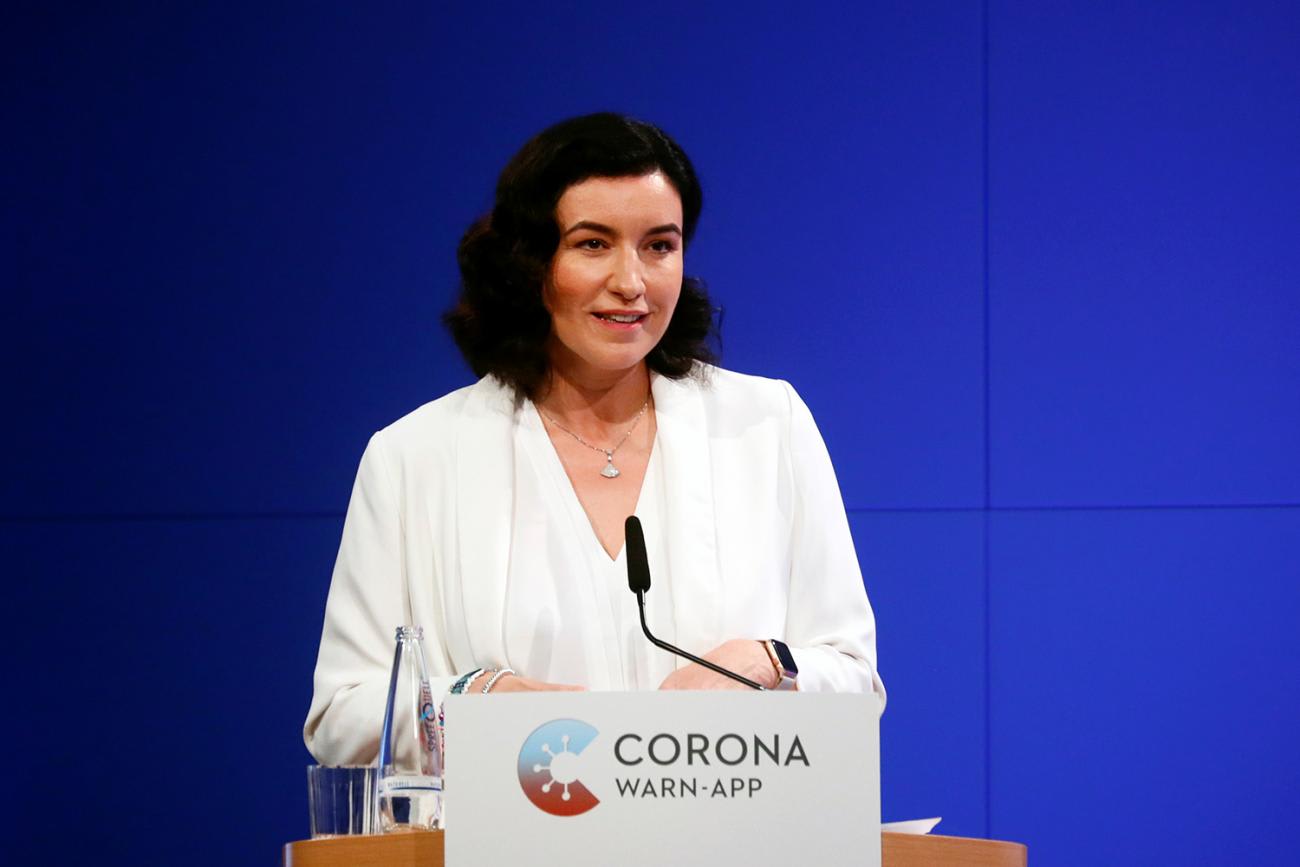Photo shows the minister at a podium speaking. 
