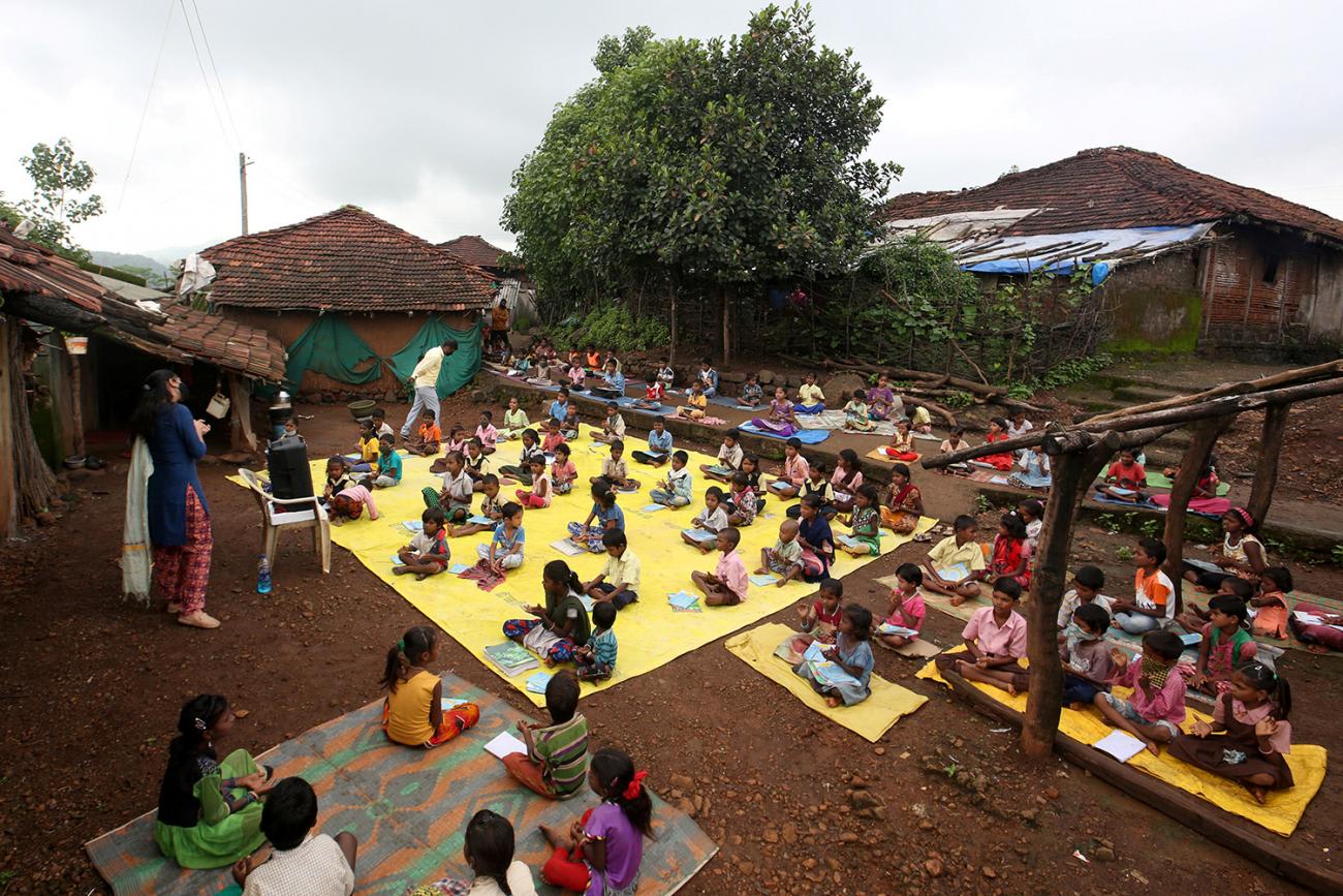 Picture shows an outdoor area with a huge group of kids seated at a safe distance from one another.