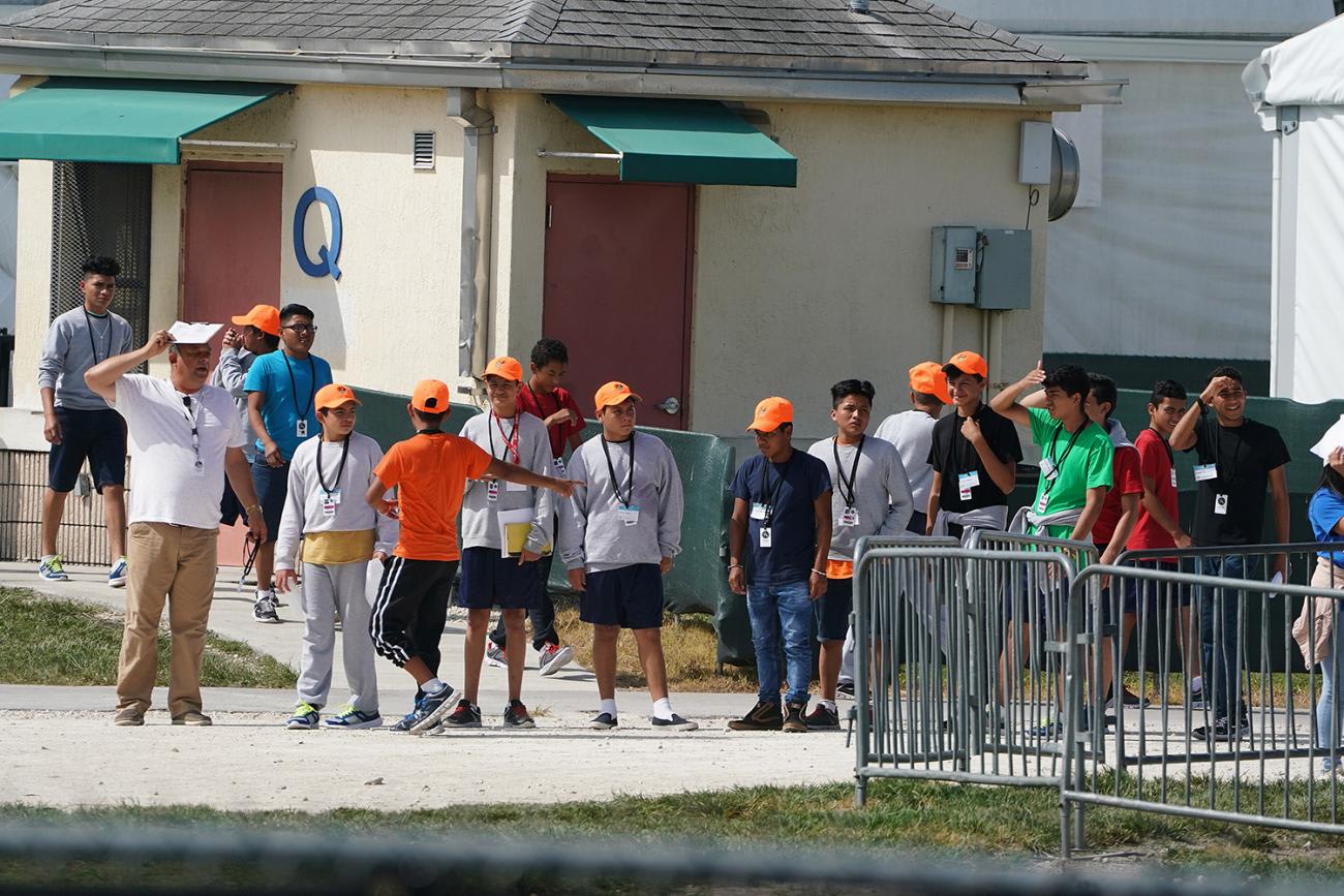 The photo shows a group of children, all with orange hats, standing in a line.