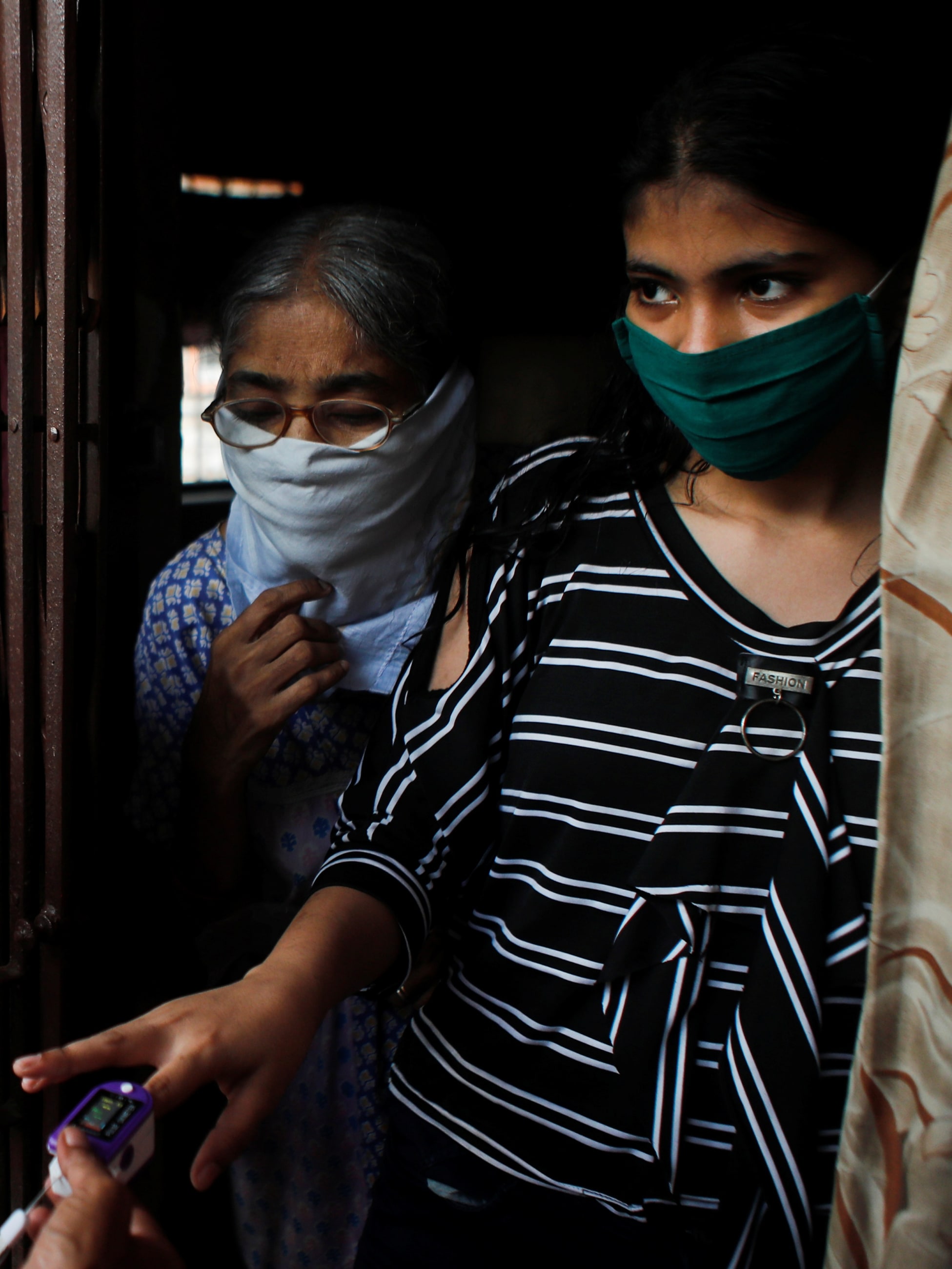 Community health volunteers check the pulse of a resident during a check-up campaign for COVID-19 in Mumbai, India.