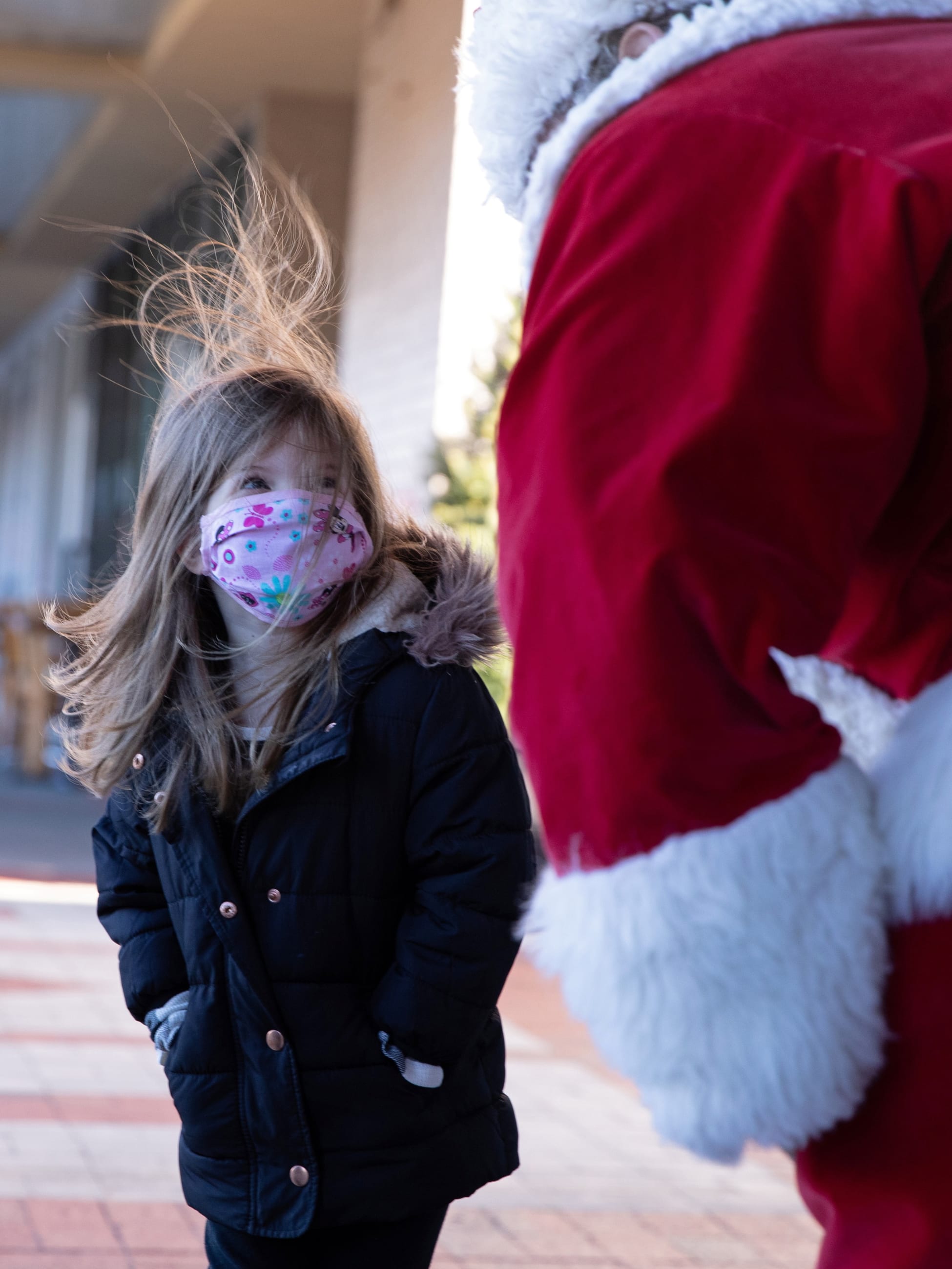 Santa Claus greets a young girl outside, both wearing masks as a precautionary measure in Queens as the global outbreak of the coronavirus disease continues in New York City on December 6, 2020.
