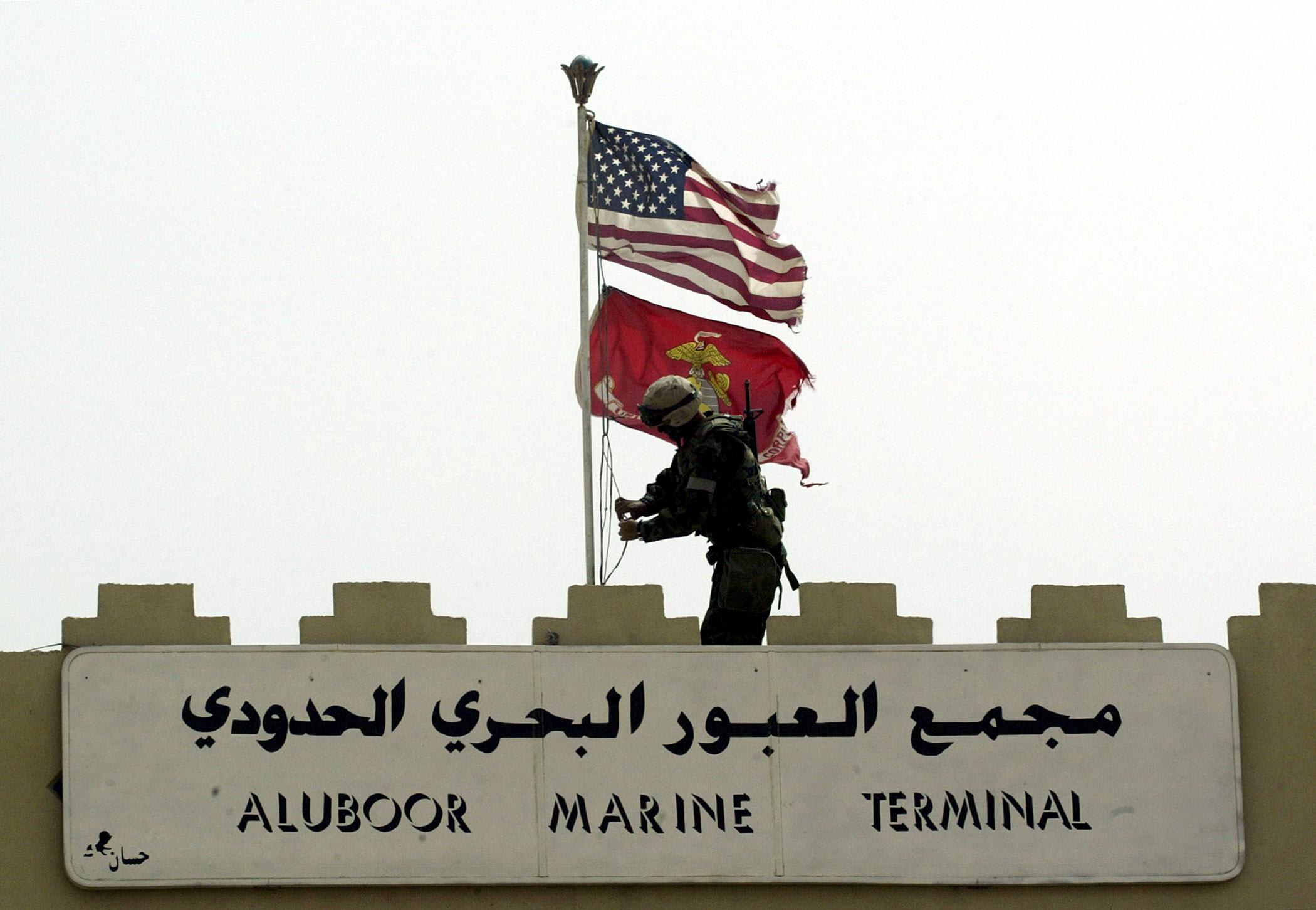 A Marine of the U.S. Marine Expeditionary Unit (MEU) Fox Company 'Raiders' replaces the Iraqi flag at the entrance to Iraq's main port of Umm Qasr on March 21, 2003