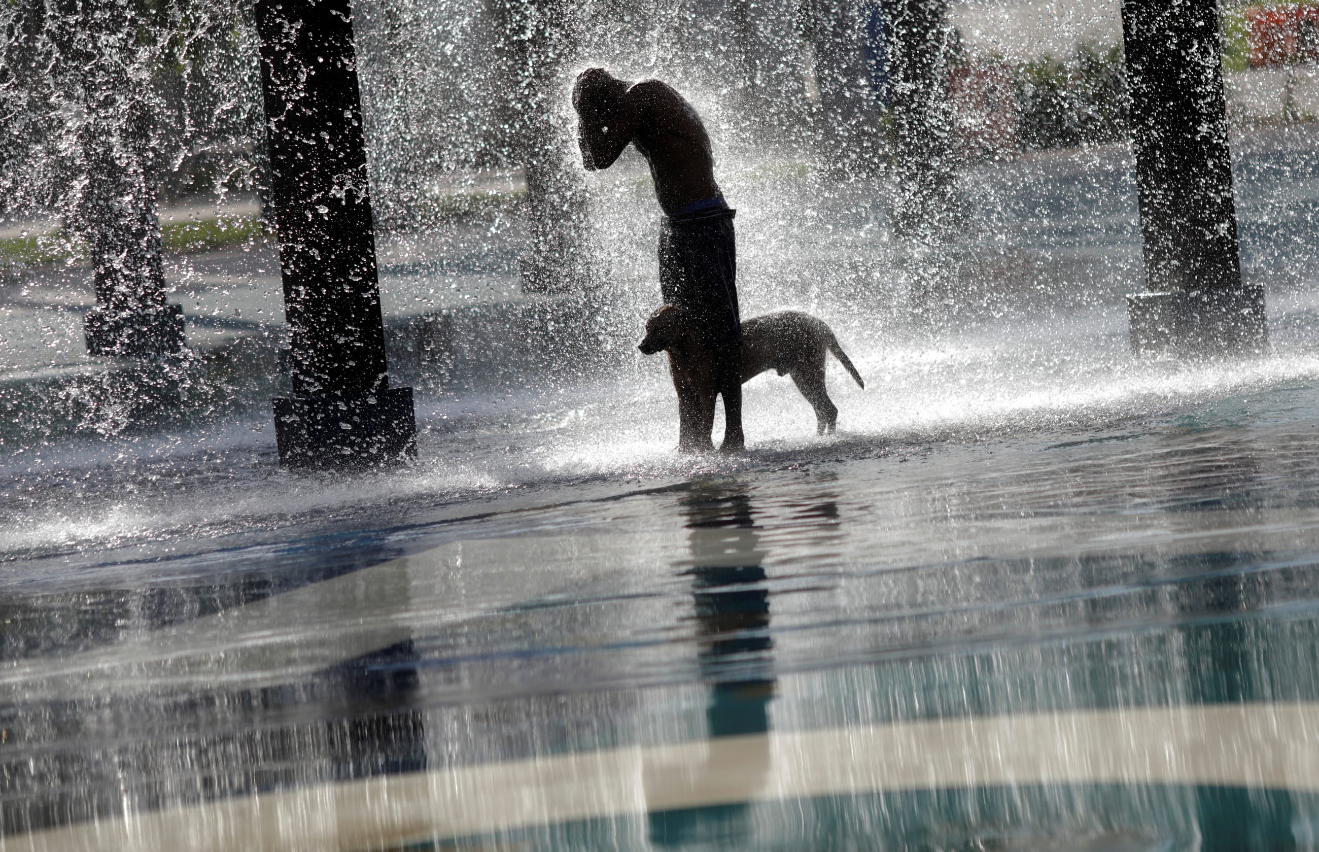 A man refreshes himself and his dog at a fountain, in Madureira Park in Rio de Janeiro, Brazil, on March 19, 2019.