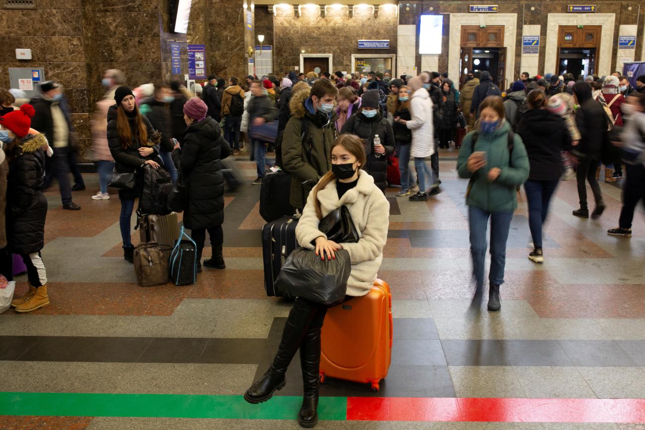 A woman sits on a suitcase at the Central Railway Station as people try to leave the city of Kyiv, Ukraine February 24, 2022.