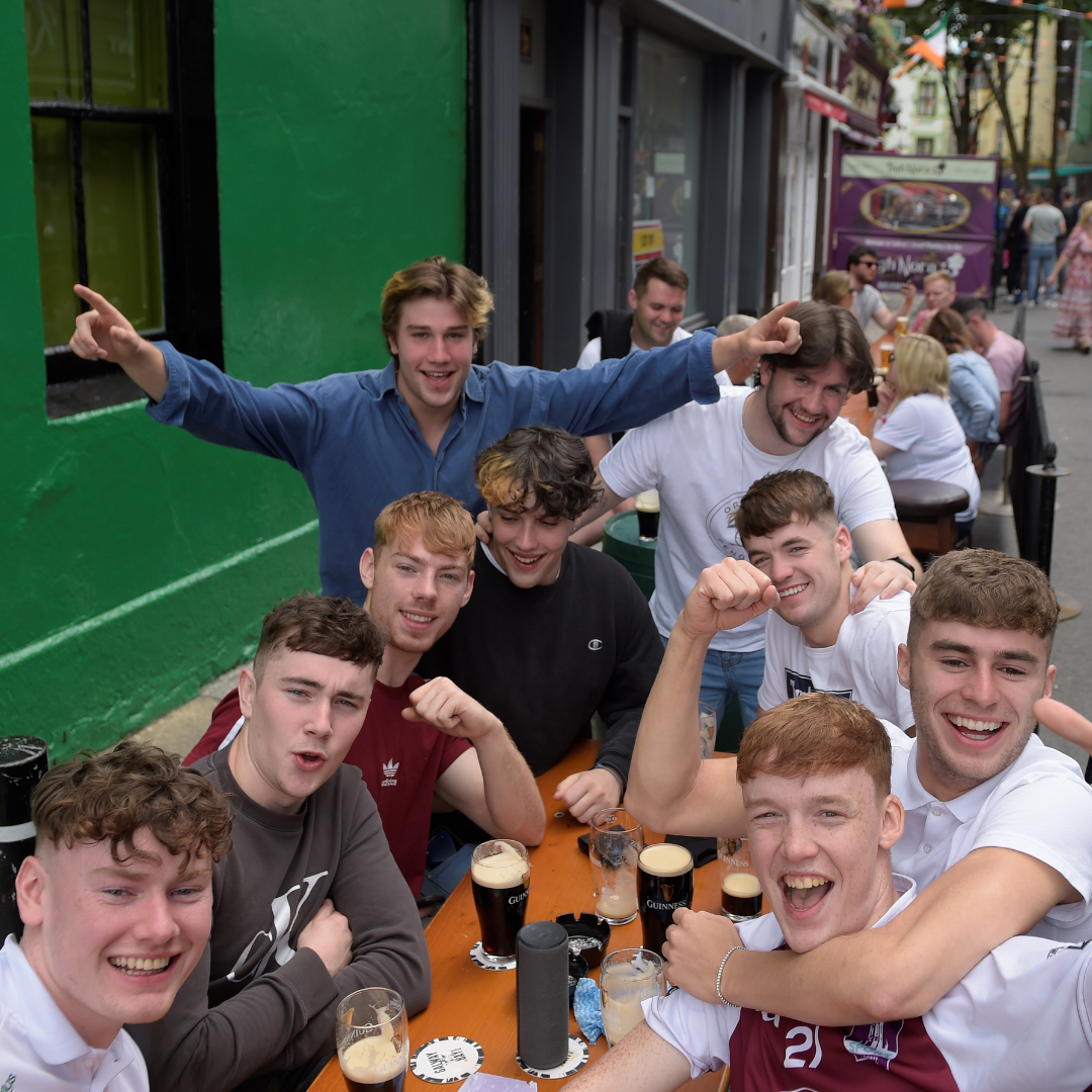 A group of friends celebrates at an outdoor table, drinking beers, laughing, and cheering as COVID-19 restrictions ease in Galway, Ireland, on June 7, 2021.