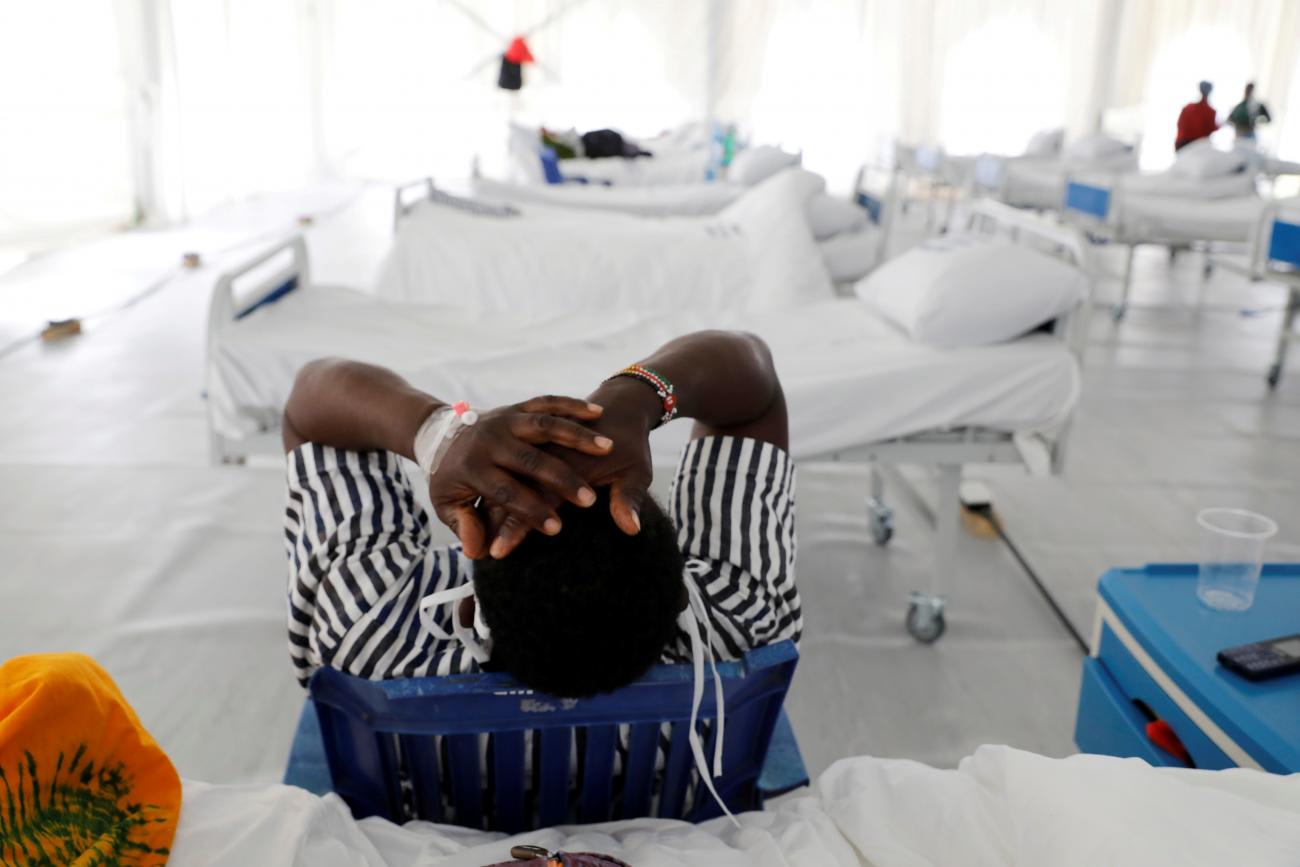 After testing for COVID-19, a patient leans back in his chair with his arms resting on his head, in a field hospital built inside a soccer stadium in Machakos, Kenya, on July 23, 2020.