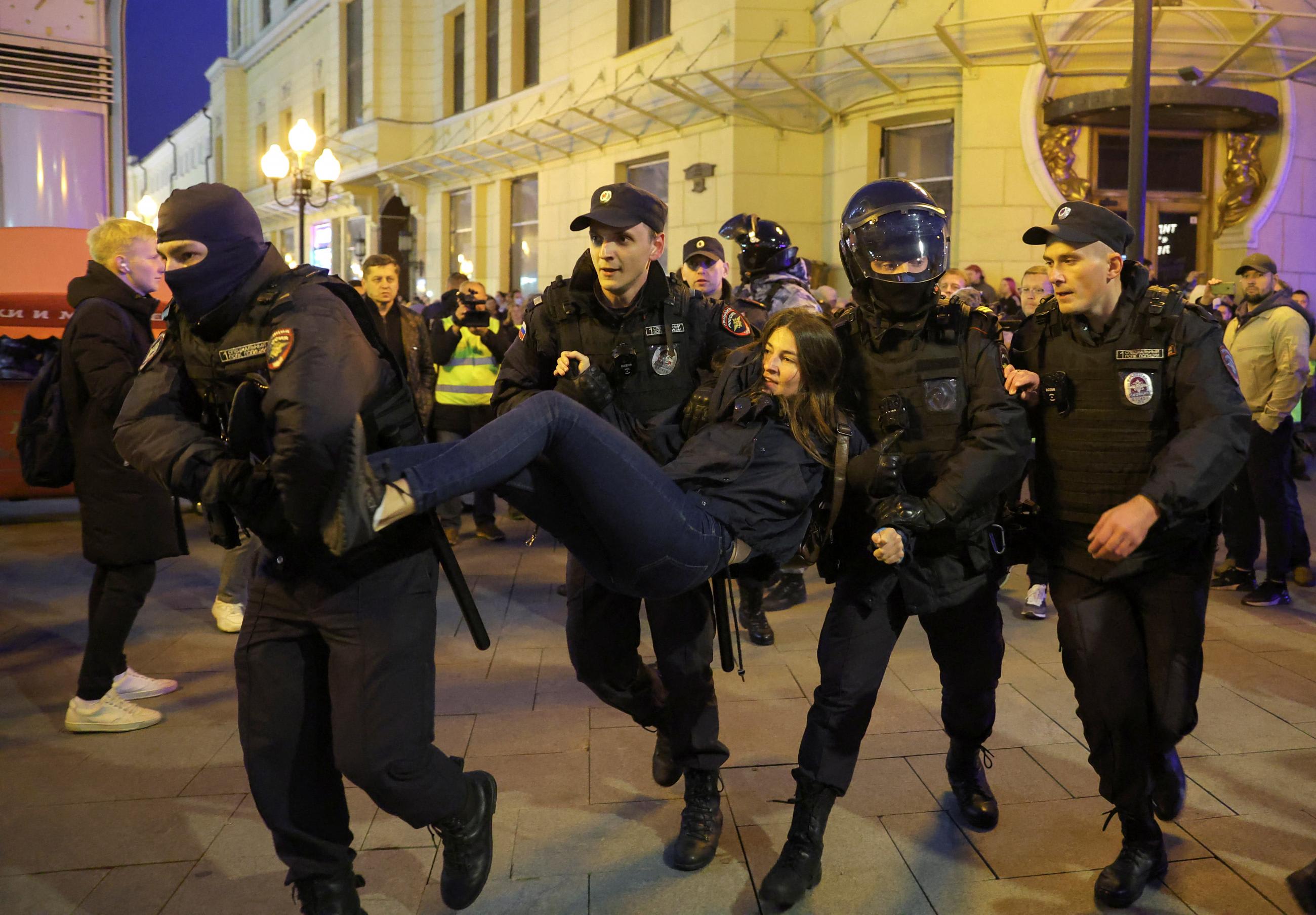 Russian police lift a young woman in the air by her arms and legs as she and others protest Putin's war in Ukraine and the Russian president's call to mobilize reservists in the armed forces, in in Moscow, Russia, on September 21, 2022.