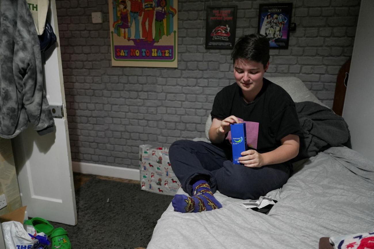 Miles Pitcher, 17, a transgender boy who told Reuters how he had turned to an online provider for private gender care after waiting years for the UK's National Health Service (NHS) to deliver it, opens a box of Testogel testosterone gel as he poses for a photo in his room in Dover, Britain, November 28, 2022.