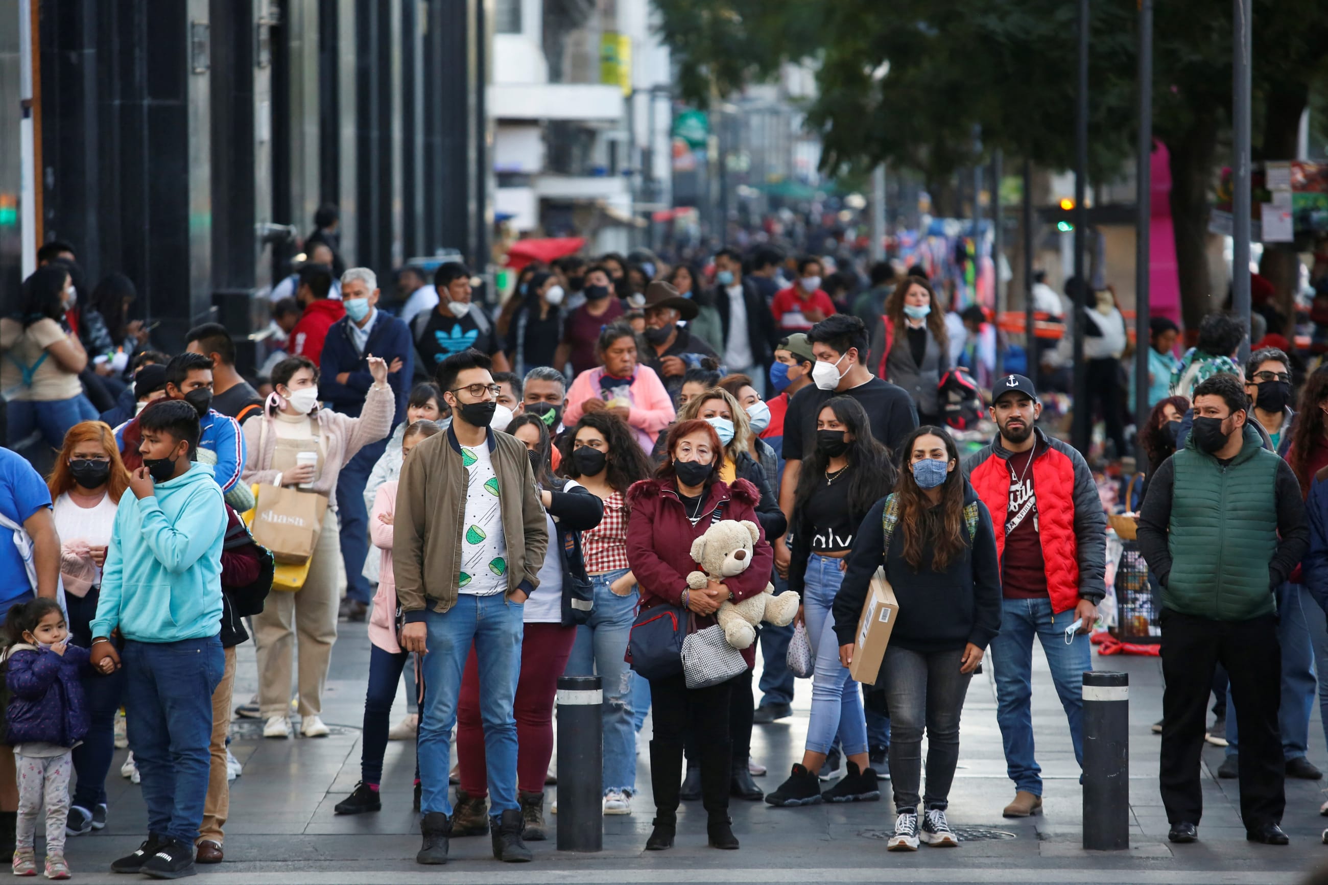 A crowd of people walk on a crowded sidewalk.