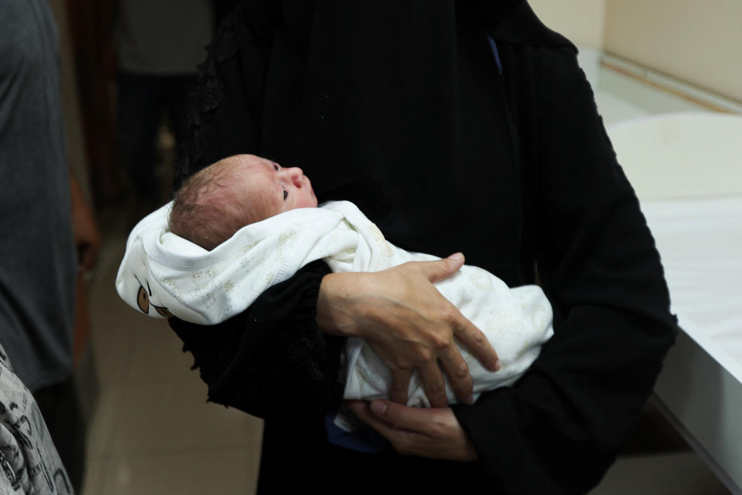 A baby is held in a person's arms amid the ongoing Israel-Hamas conflict.