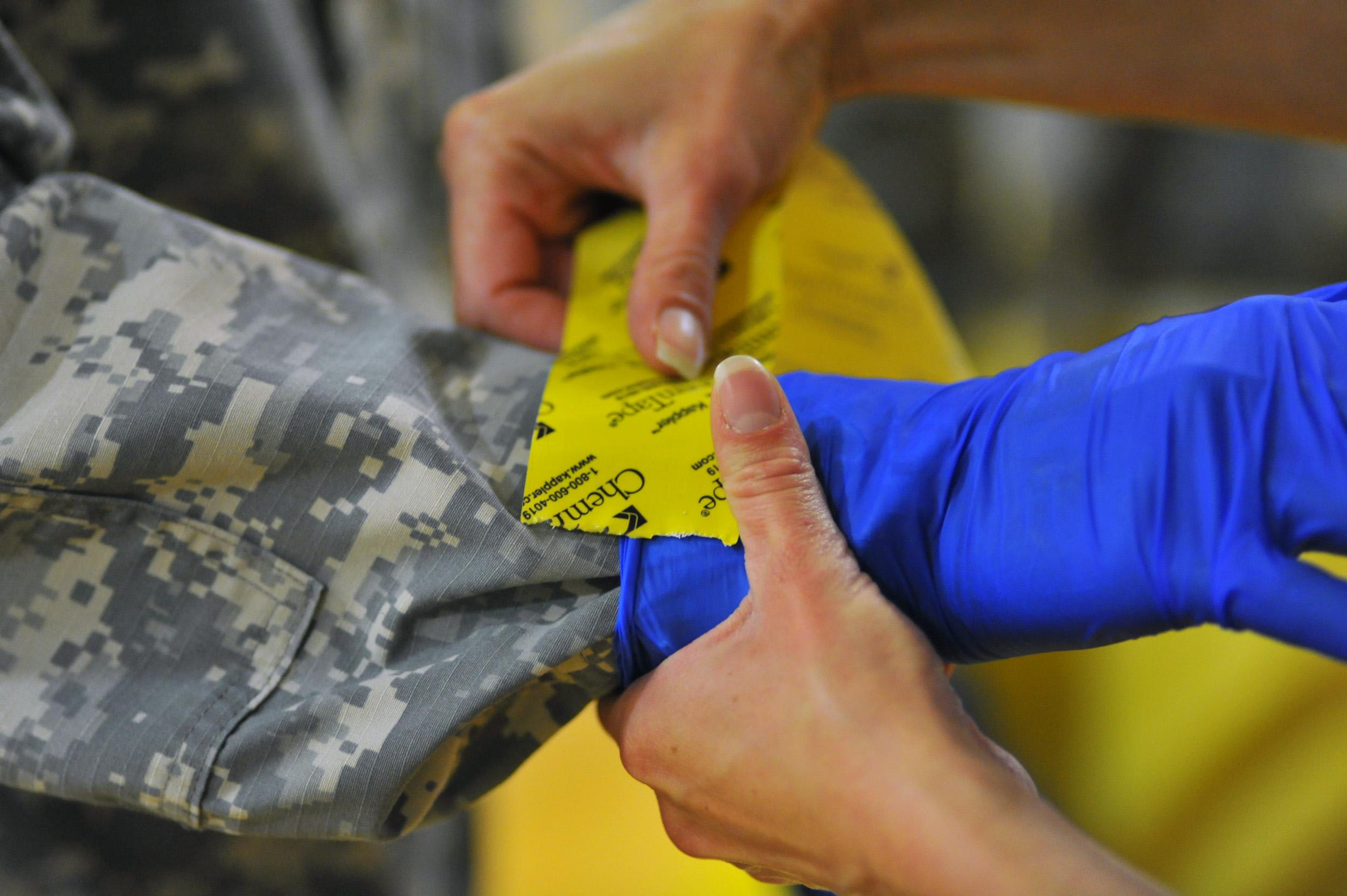 Ondraya Frick from U.S. Army Medical Research Institute of Infectious Diseases demonstrates how to properly apply tape to gloves for U.S. Army soldiers.