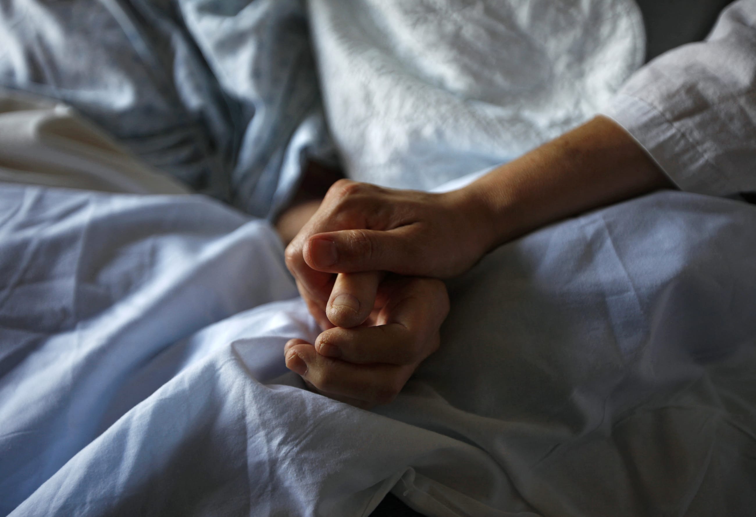 A woman holds the hand of her mother who is dying from cancer during her final hours, at a palliative care hospital, in Winnipeg, Canada, onJuly 24, 2010.