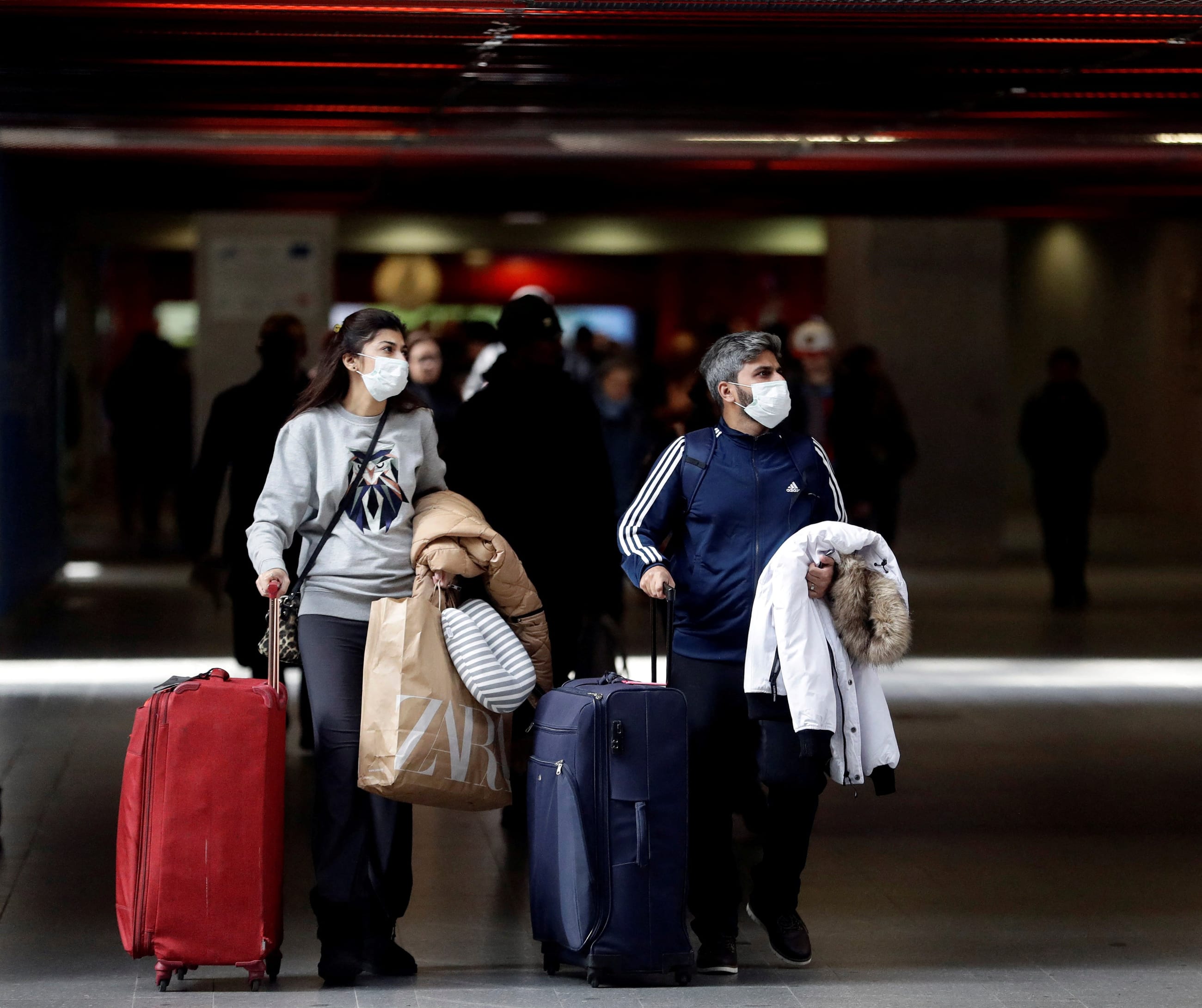 People wearing masks are seen at a railway station.