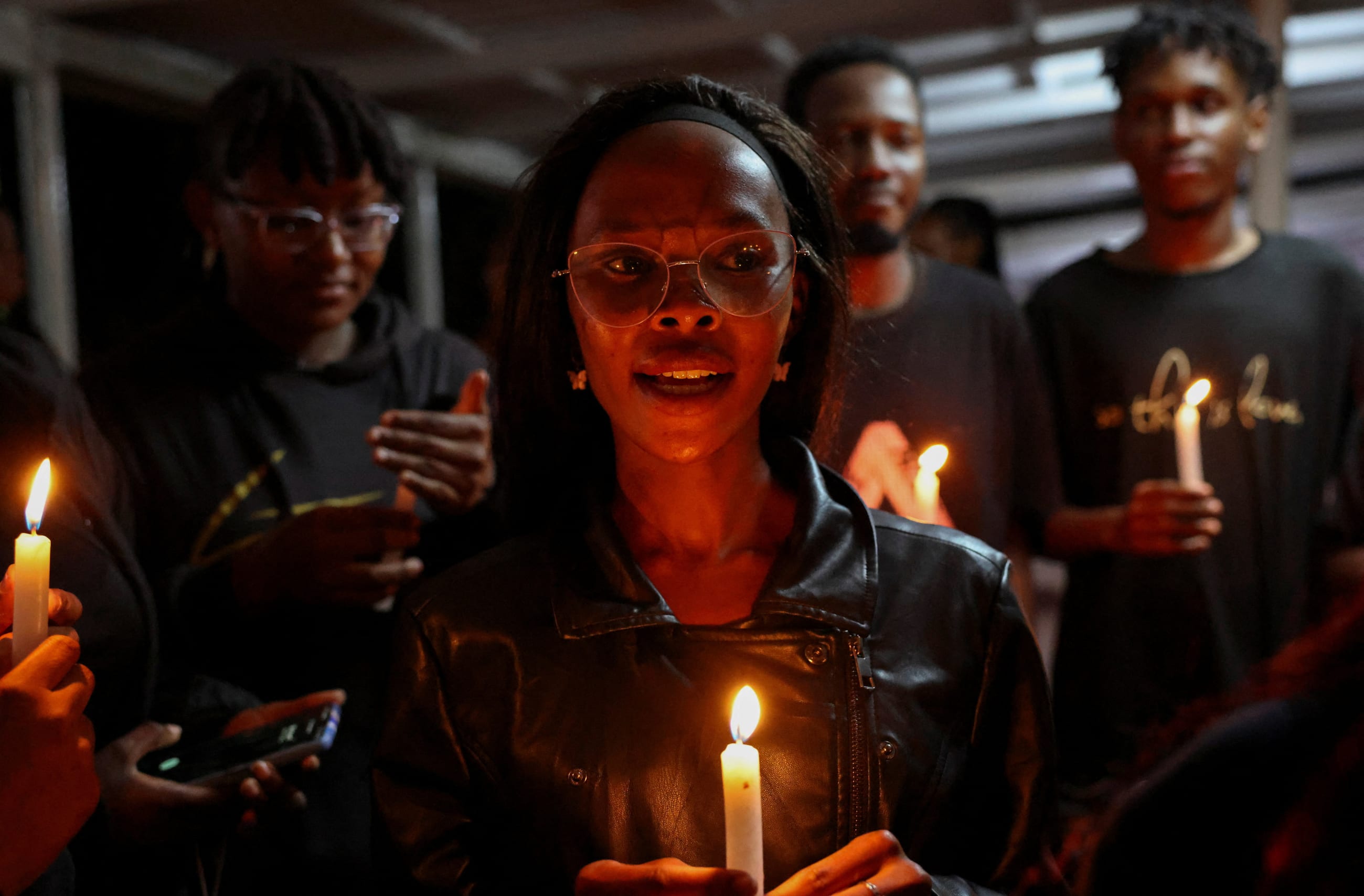 People hold candles at a vigil to raise awareness about gender-based violence and honor the lives of women lost to femicide in higher learning institutions, in Juja, Kenya, on April 11, 2025.