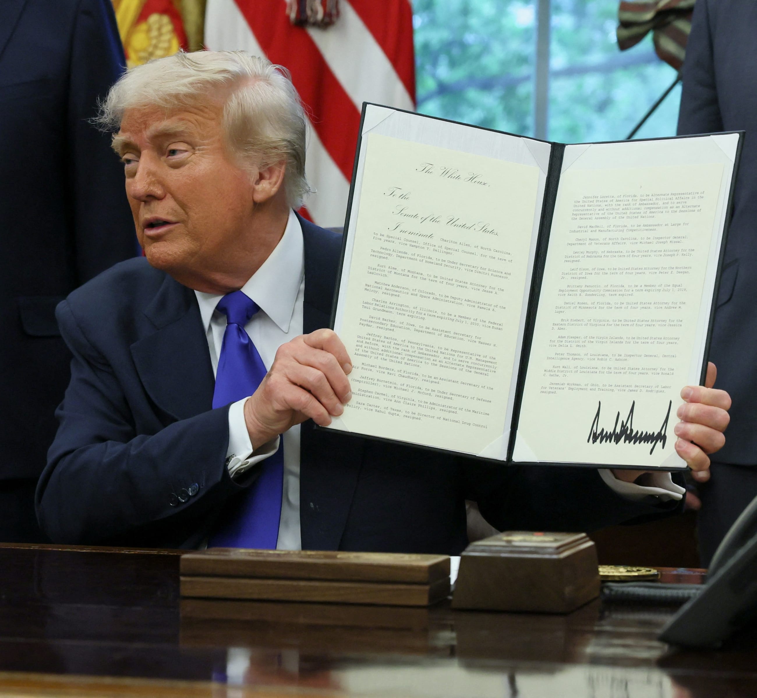 U.S. President Donald Trump shows a signed document as he signs executive orders and proclamations, in the Oval Office at the White House, in Washington, DC, on May 5, 2025.
