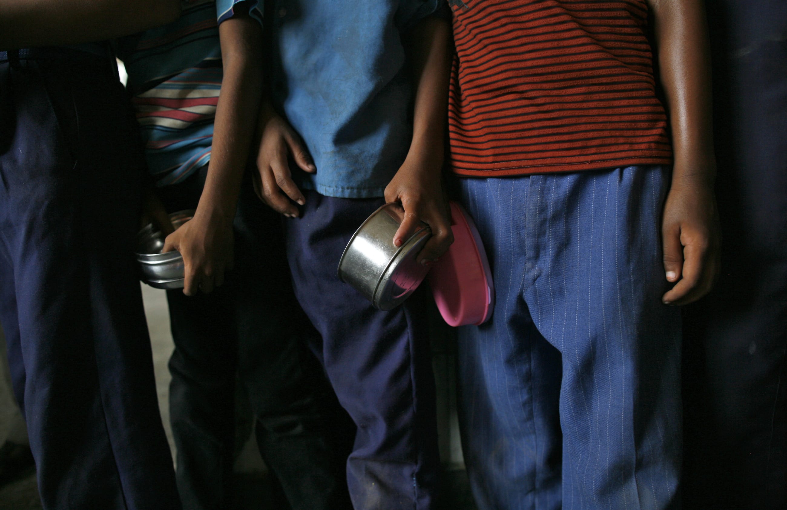 School boys carry their tiffin boxes as they wait to receive their free mid-day meal, distributed by a government-run primary school, in New Delhi, India, on July 19, 2013.