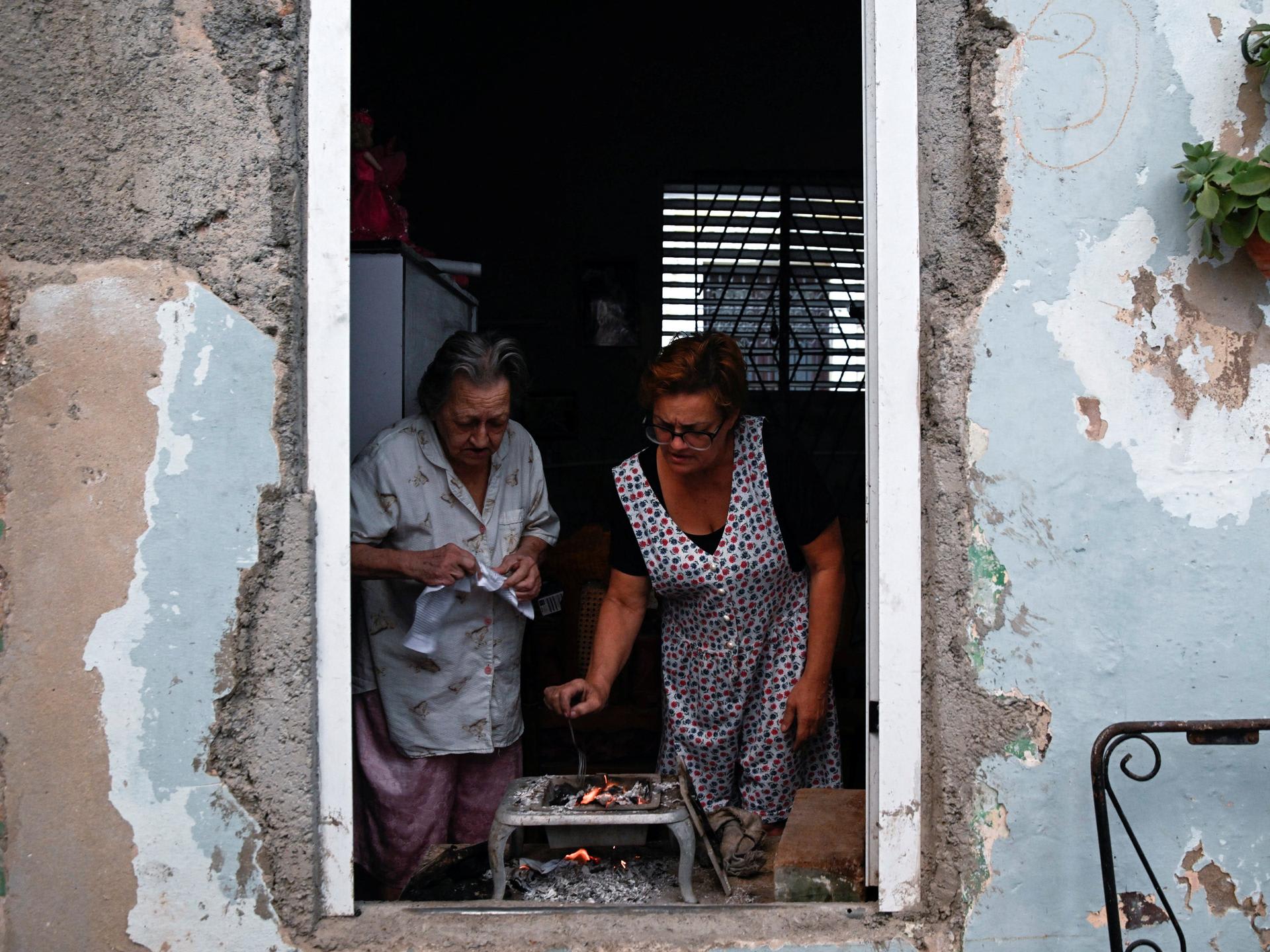 A street veTwo women cook dinner after Cuba's national electric grid collapsed for the second time in a week, amid the U.S.-imposed oil blockade, in Havana, Cuba, on March 21, 2026.ndor selects cigarettes for a customer, in Abidjan, Ivory Coast, on May 27, 2024. 