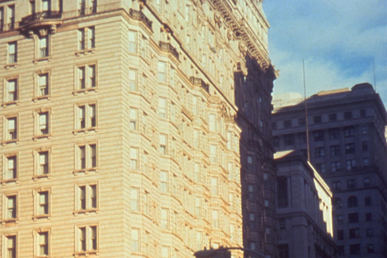 The photo shows an old, magnificent stone building against a bright blue sky. It's a grainy photo, suggestive of a poor quality color film stock or a cheap camera.