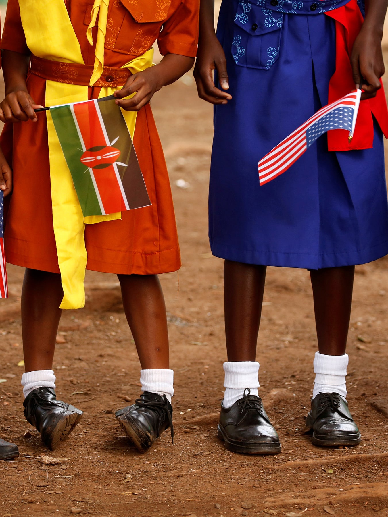 The photo shows four girls from the stomach down holding flags.