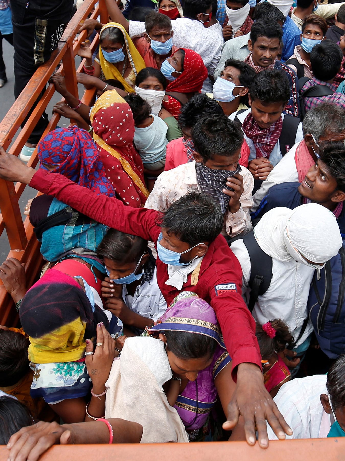The photo shows the back of a flatbed truck from above. People are packed in the vehicle beyond capacity, sardined together for what looks like a bumpy ride.