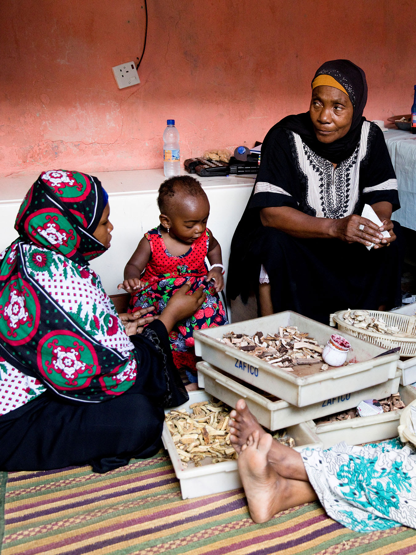 The photo shows the healer facing the camera and sitting between two other women and a child.