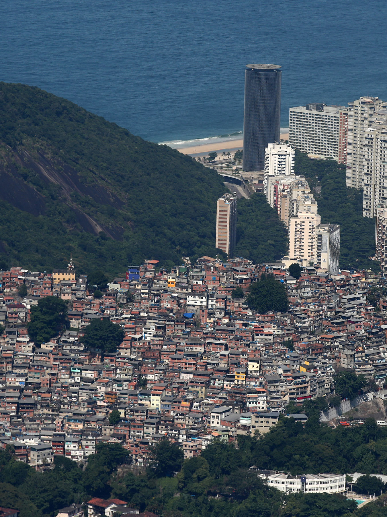 The photo is a gorgeous shot taken from the sky showing the slums cascading down the mountain to the coast, which is dotted with modern skyscrapers, and the ocean beyond.