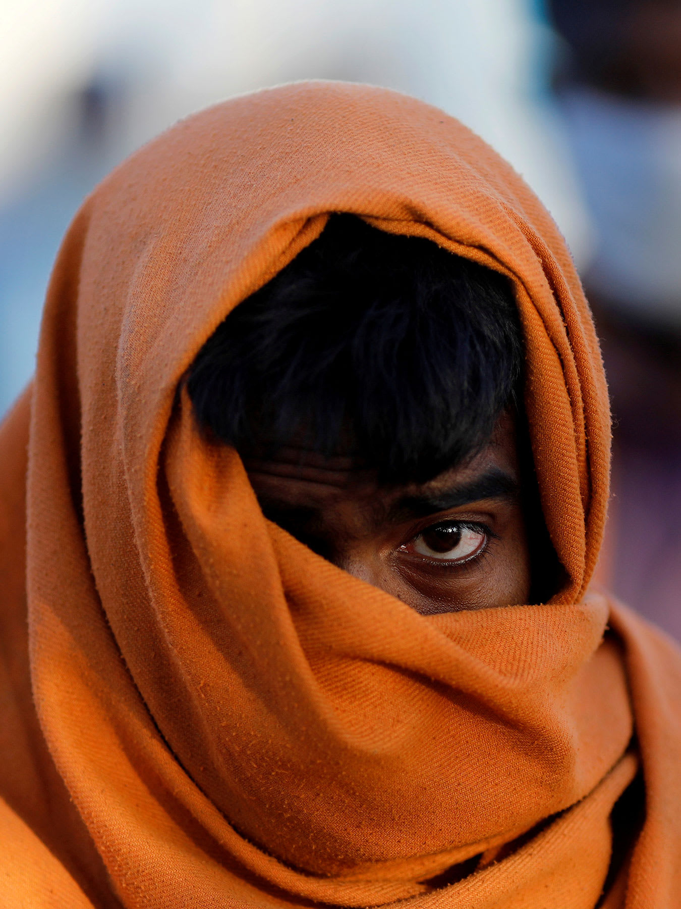 The image is very striking showing the man with a large wrap around his head and mouth against a creamy, out of focus, colorful background.