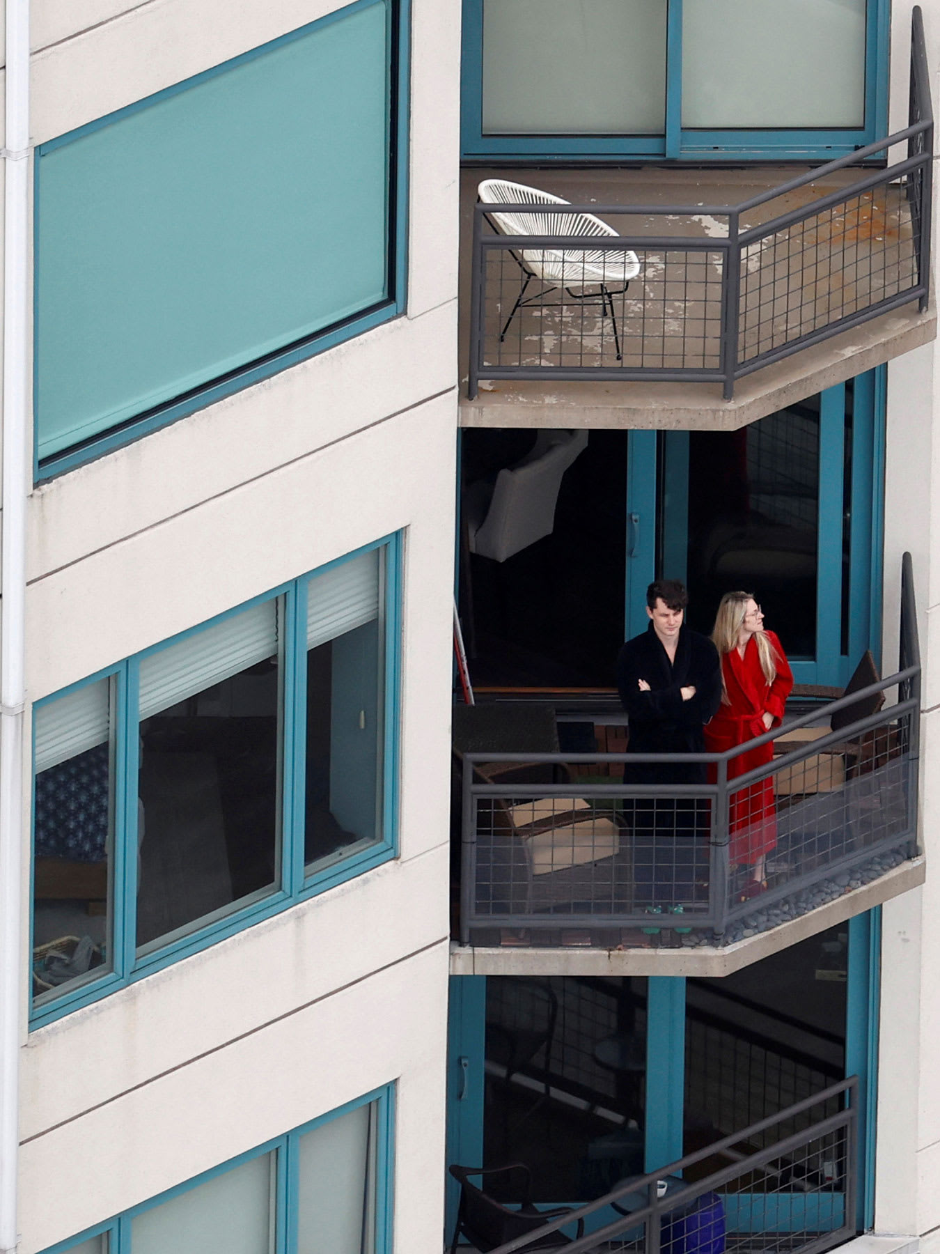 The photo shows a couple on their balcony looking down.