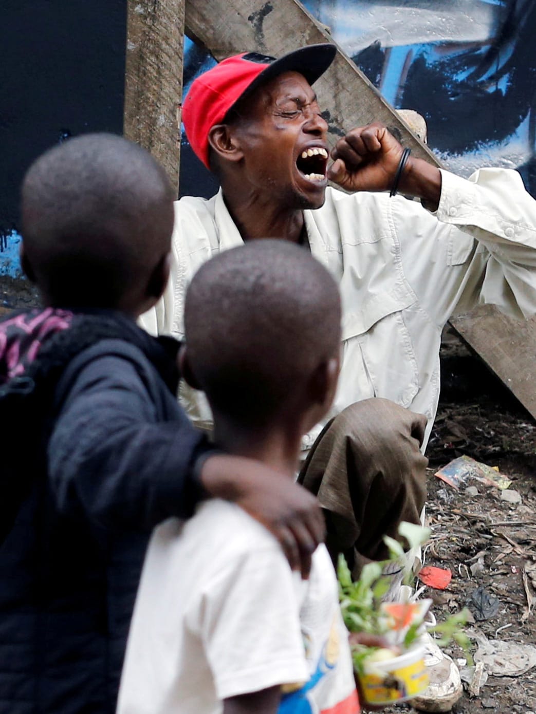 This is a powerful image of two children looking at a man who is coughing into his had with his head turned.