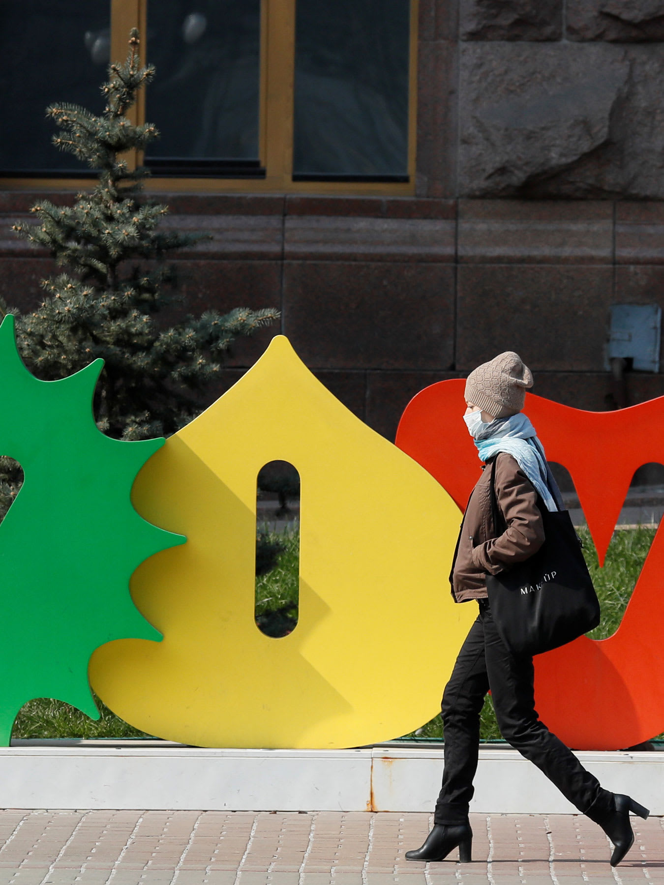 This is a striking photo with a stylish woman walking in front of a sign with the city's name.