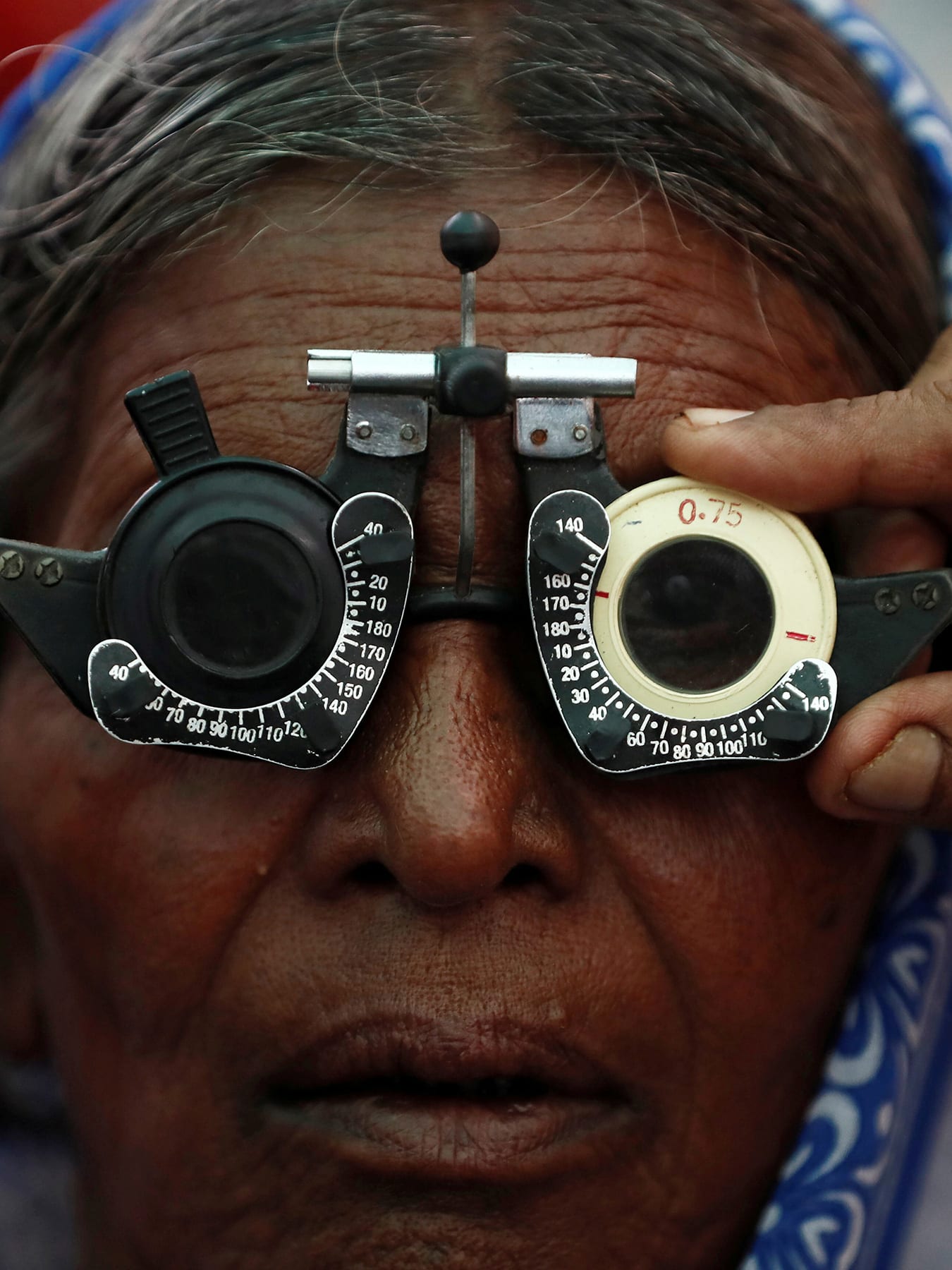 The photo shows an older woman with testing glasses on her face. 