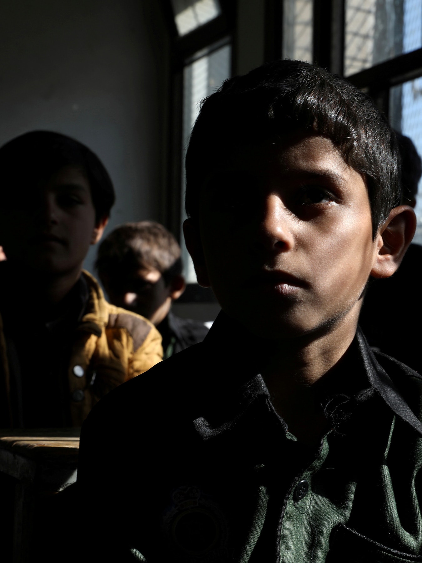 The photo shows a darkened classroom with several students facing the camera.