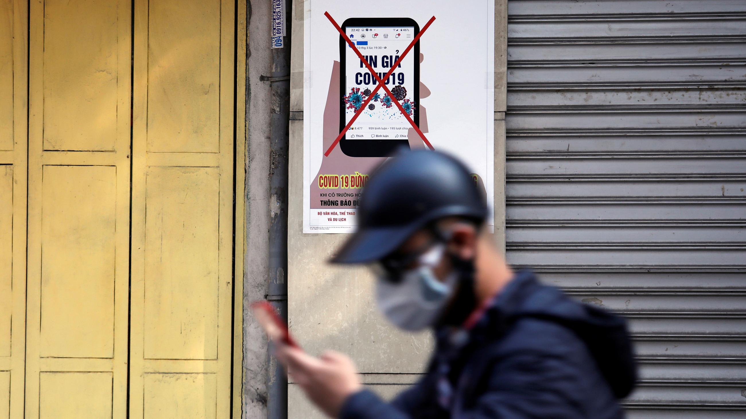 Picture shows a man with a hat walking out of focus in the foreground against a PSA picture posted on a wall.