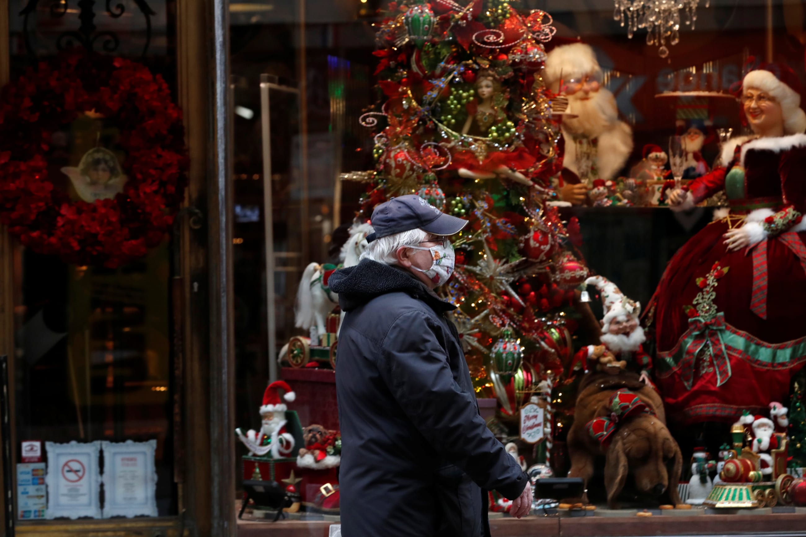 An elderly man wearing a protective face mask walks in front of a Christmas store display in downtown Budapest, after Hungarian government imposed a nationwide lockdown to contain the spread of the coronavirus disease (COVID-19)
