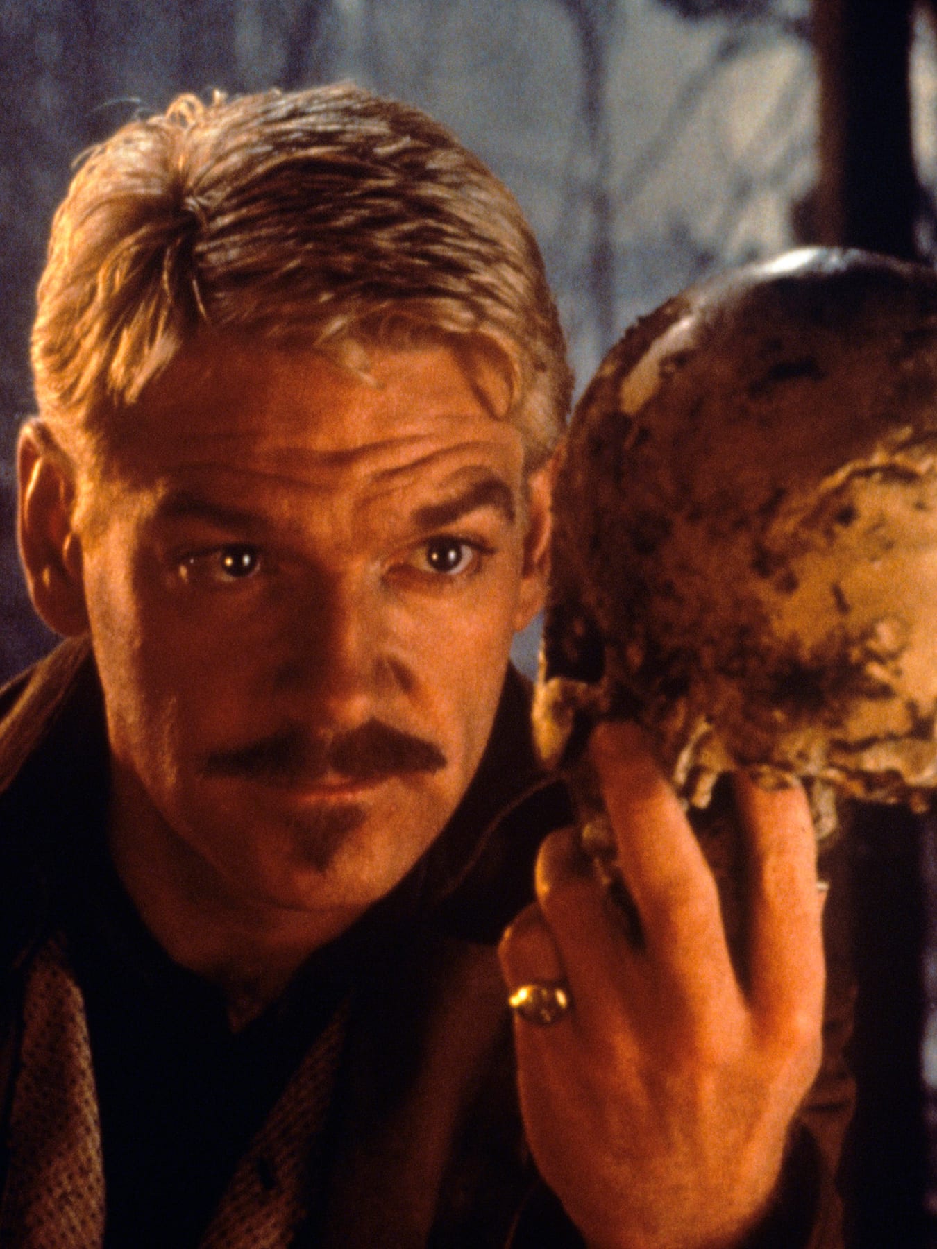 The photo shows the actor bathed in orange light and dressed in period garb holding a skull in a contemplative pose.