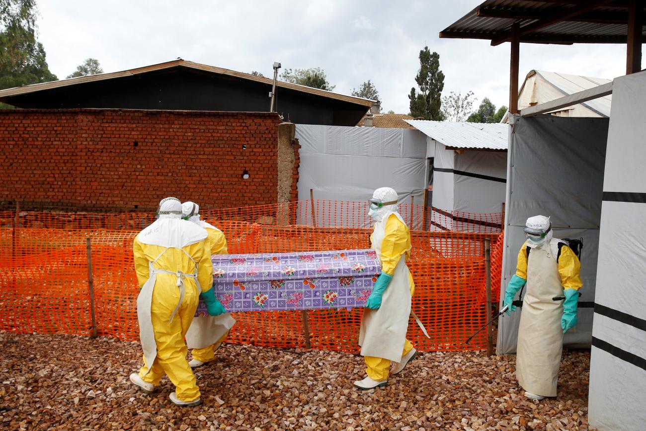 Health workers dressed in Ebola protective suits carry a coffin with the body of Congolese woman