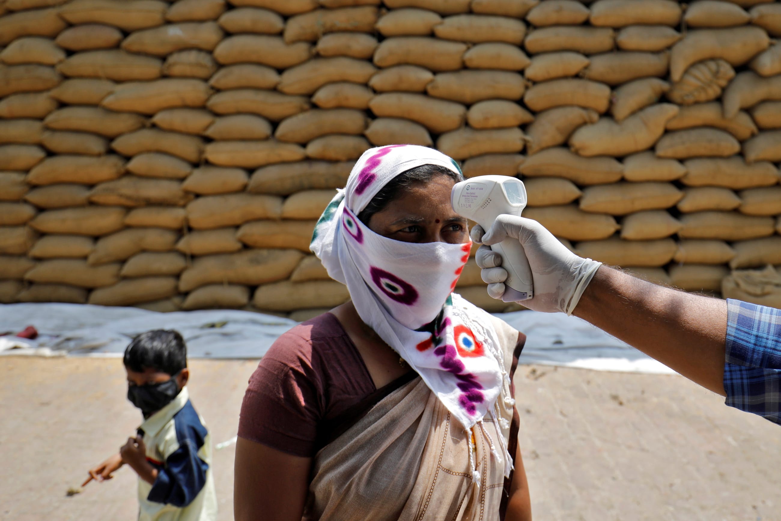 A healthcare worker checks the temperature of a rice mill worker during a coronavirus disease (COVID-19) vaccination drive at Bavla village on the outskirts of Ahmedabad, India, April 13, 2021.