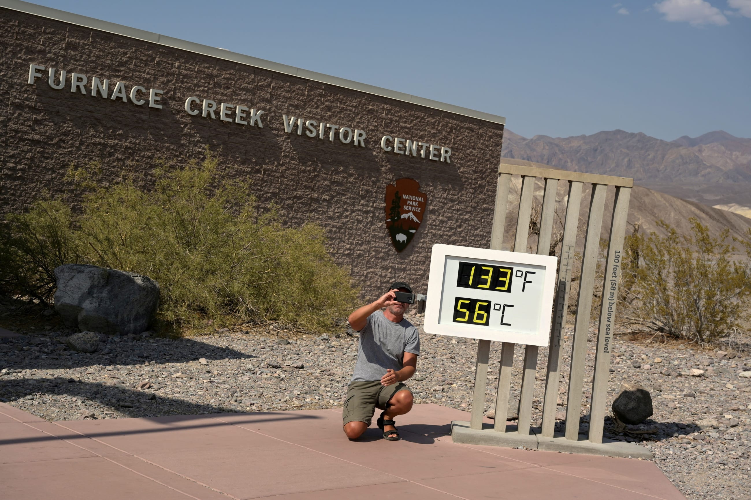 A man poses for a photo next to a thermometer in Death Valley, California on July 11, 2021.