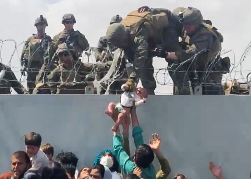 A baby is handed up to the U.S. Army over a perimeter wall at the airport in Kabul, Afghanistan, August 19, 2021 as Afghan civilians and U.S. citizens evacuated the city. 