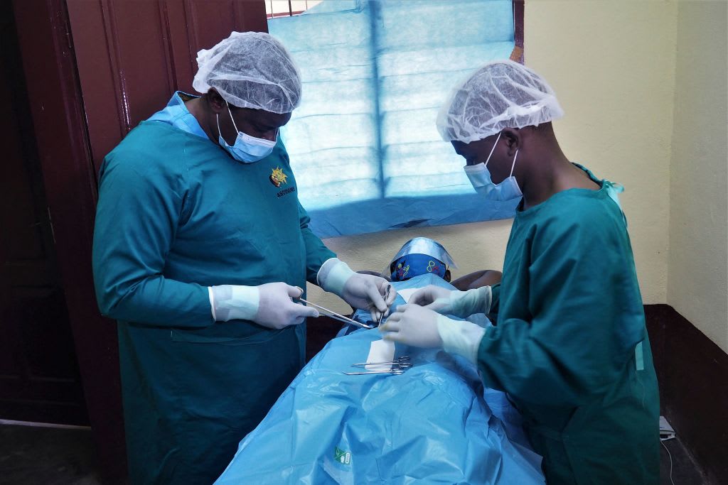Doctor Georges Bwelle (L), head of the visceral surgery department at the Yaounde Central Hospital, and one of his colleagues operate on a patient at the Nkongsamba prison in Nkongsamba, Cameroon, on July 17, 2021.