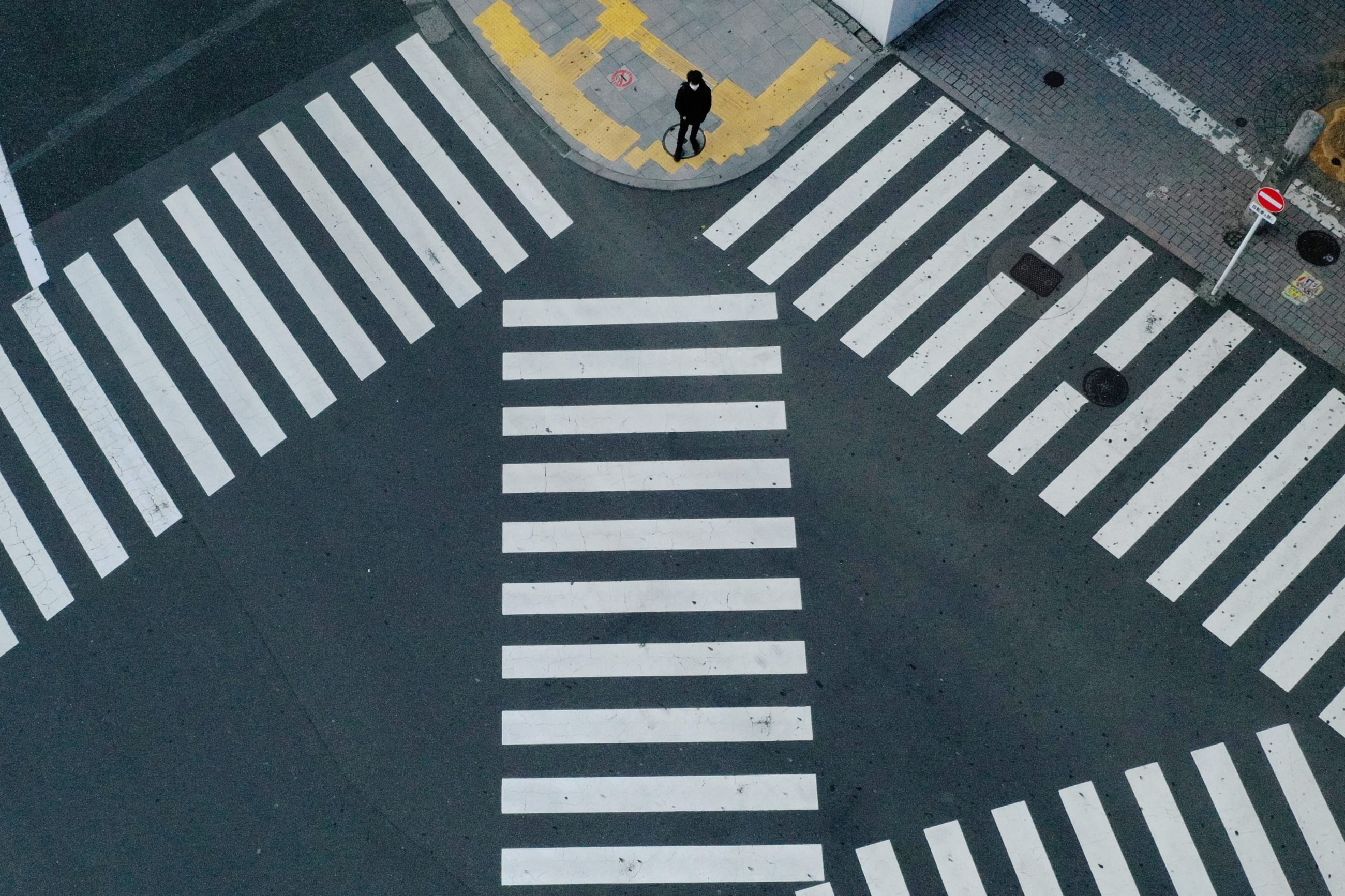 A man waits to cross a street in front of Shinjuku Station, a normally crowded street during the weekend, after the government expanded a state of emergency to include the entire country last week following the coronavirus disease (COVID-19) outbreak, in Tokyo, Japan, April 19, 2020.
